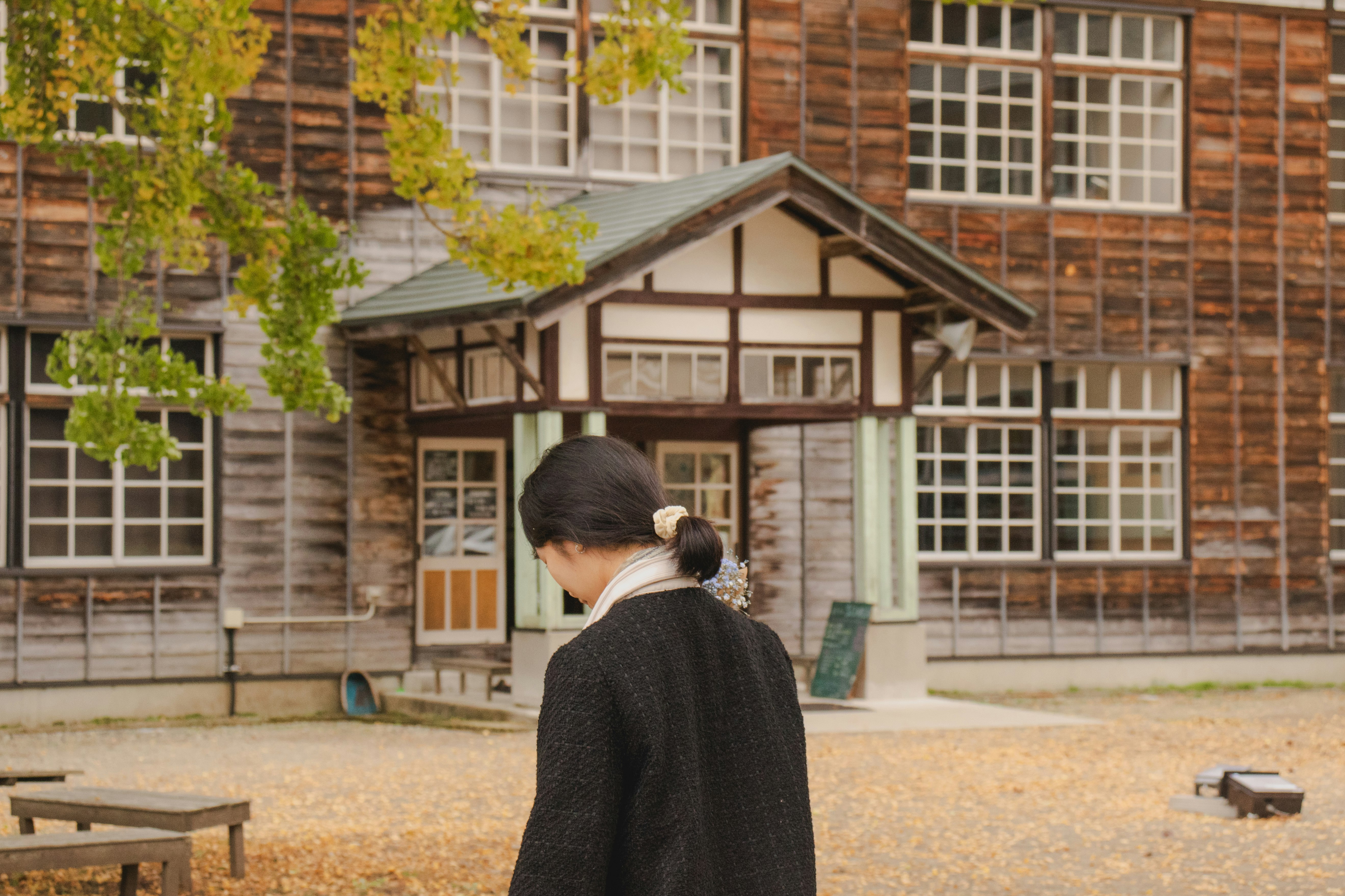 中庭で背を向けて立つ人物と木造の建物