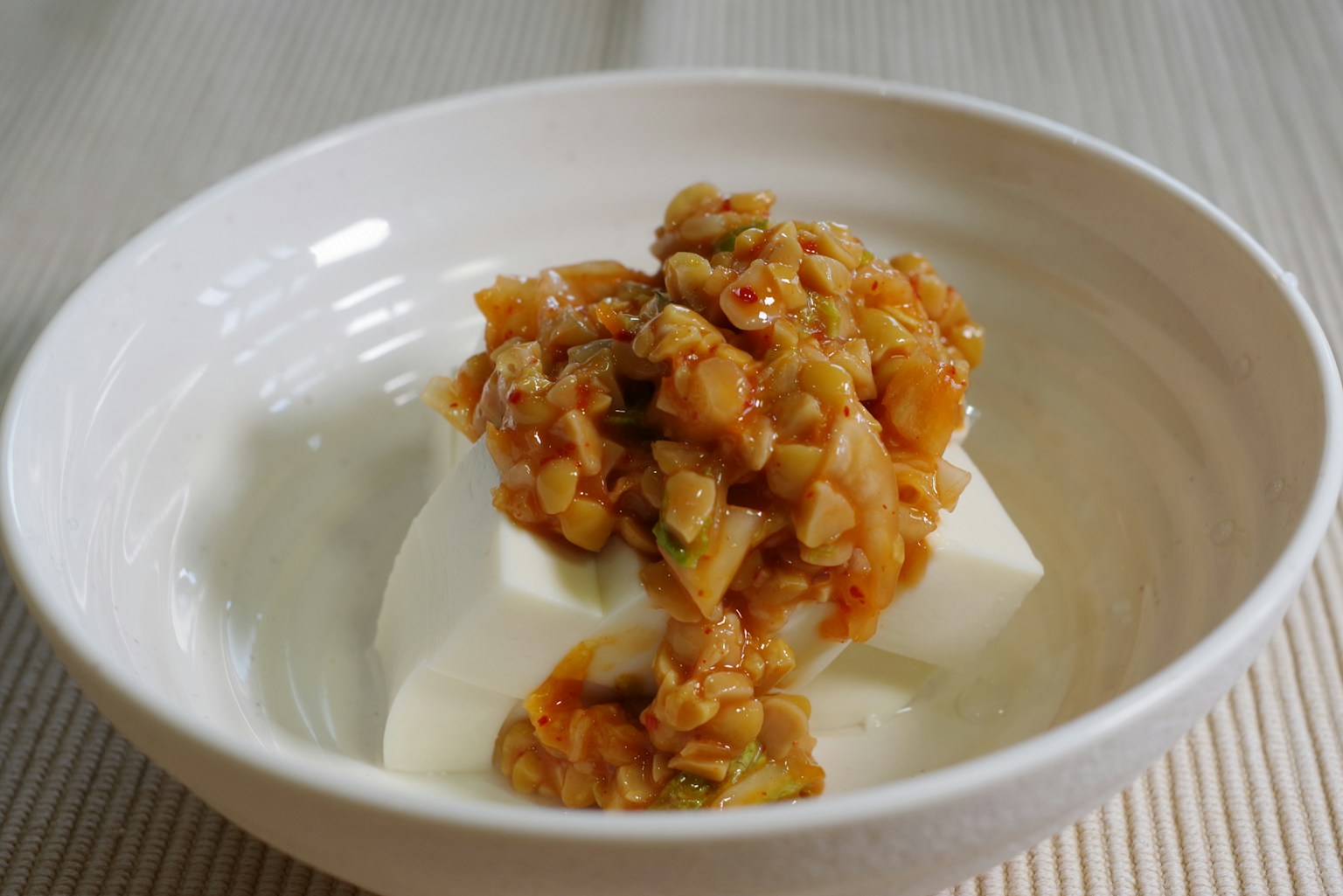 Ciotola bianca con tofu guarnito con una salsa dolce