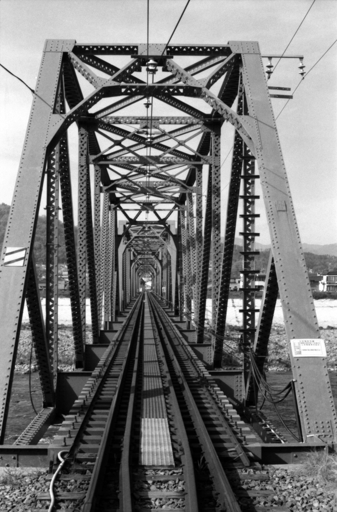 view down railway tracks on a steel truss bridge