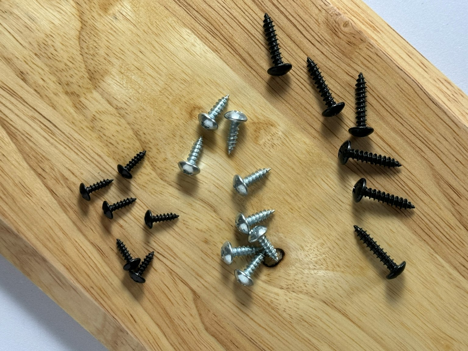 Une collection de vis noires et argentées disposées sur une planche en bois
