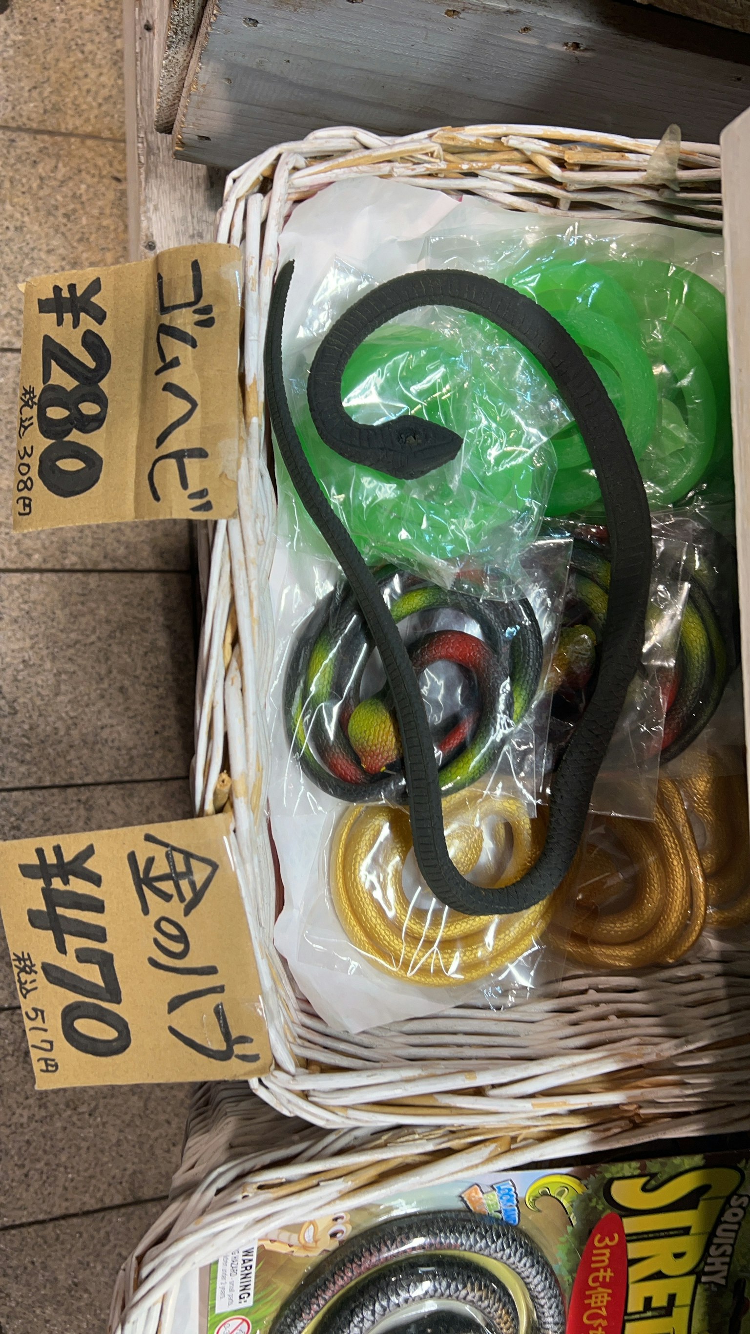 Bunte Spielzeuge und ein schwarzes, schlangenförmiges Objekt in einem Korb