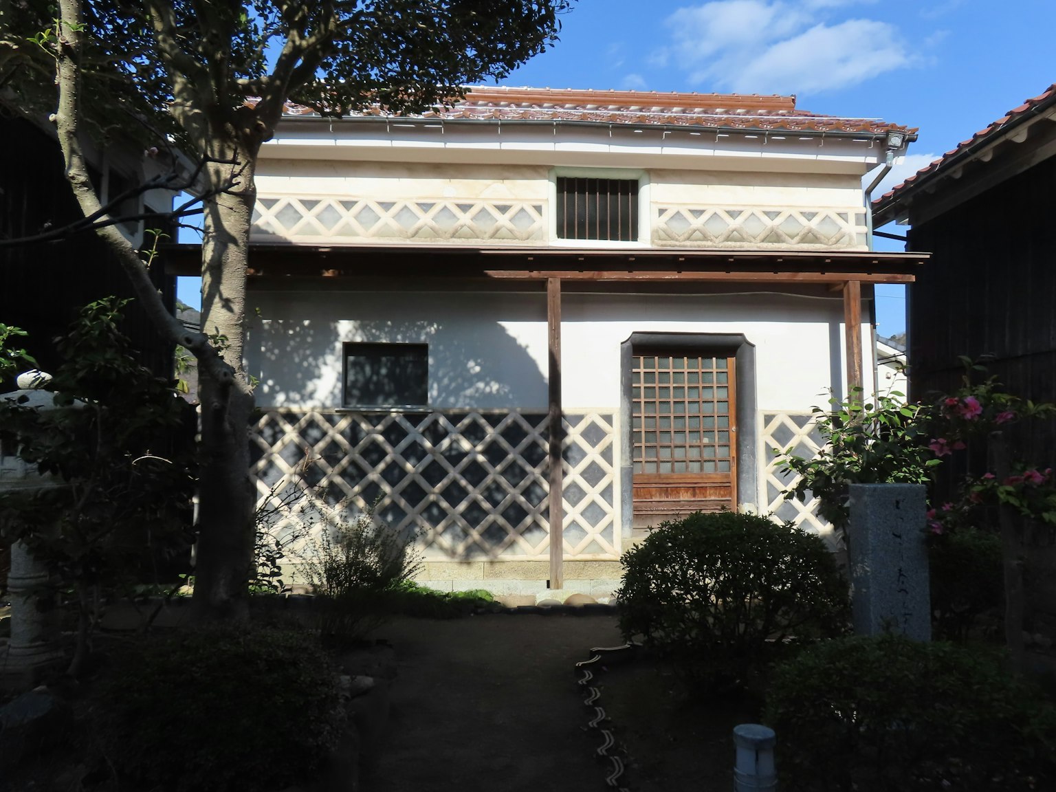 Exterior de una casa japonesa tradicional con jardín exuberante y cielo azul