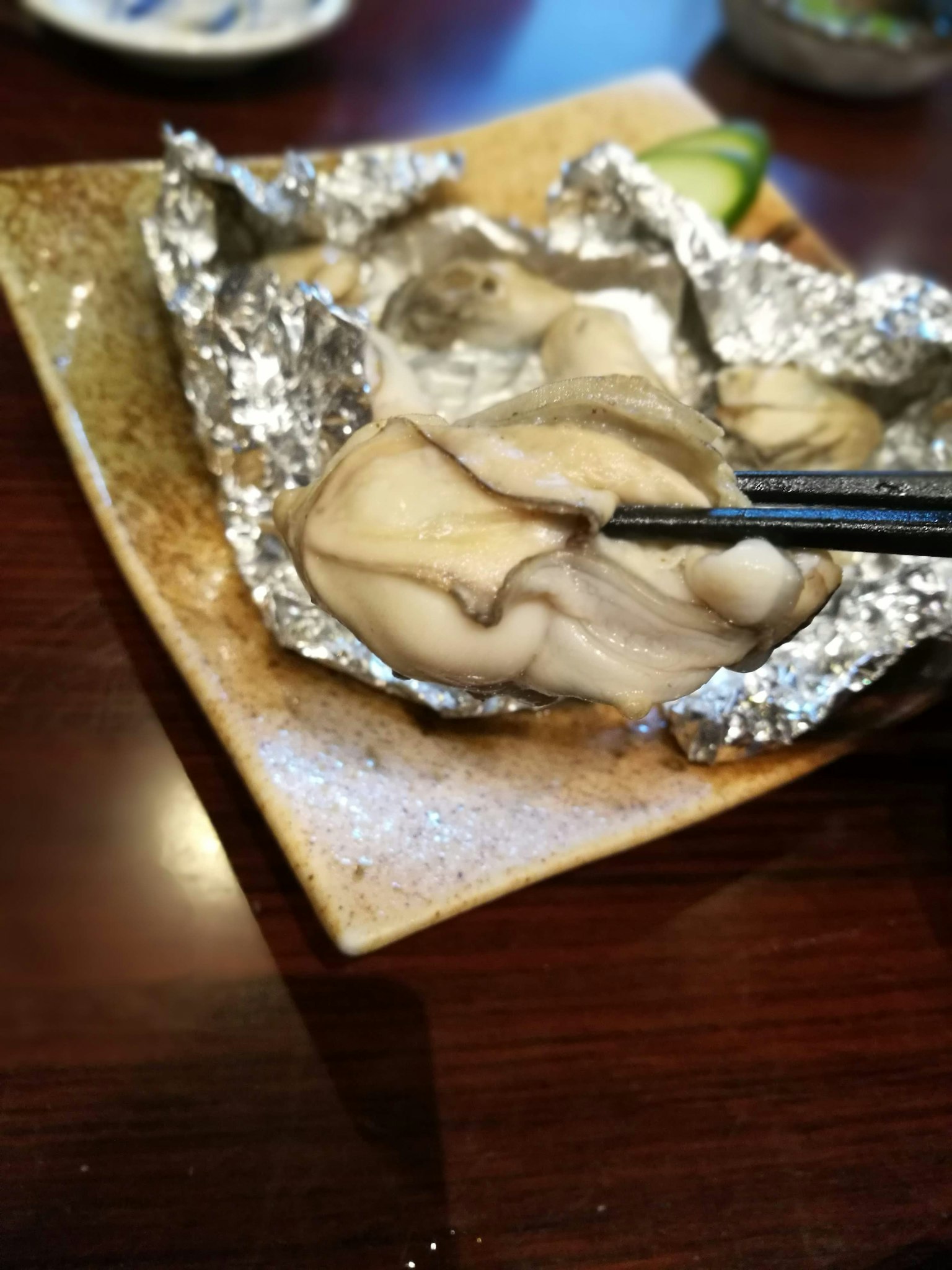 生蠔放在盤子上用鋁箔包裹著，用筷子夾著
