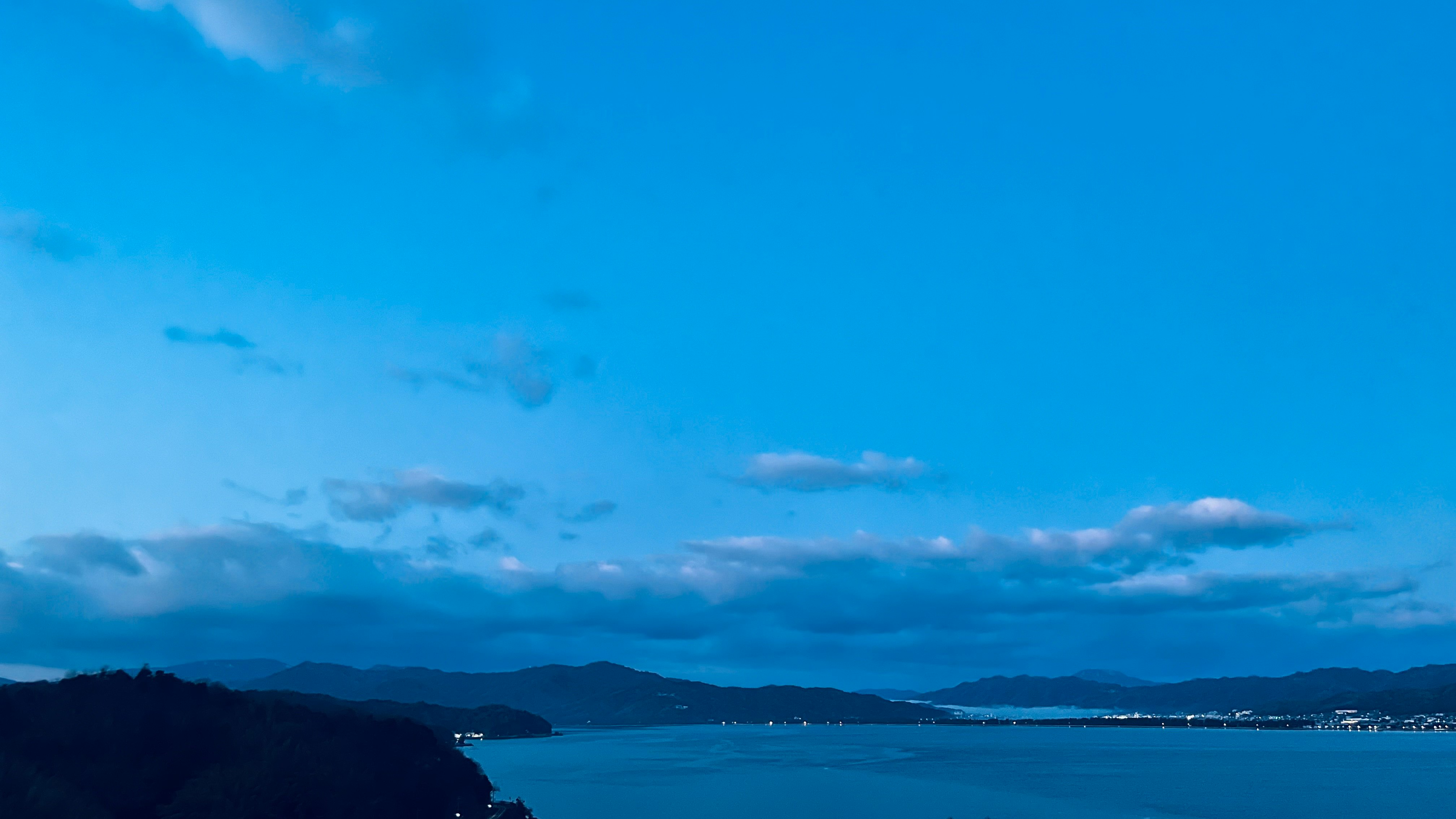 Paesaggio marino con montagne lontane sotto un cielo azzurro