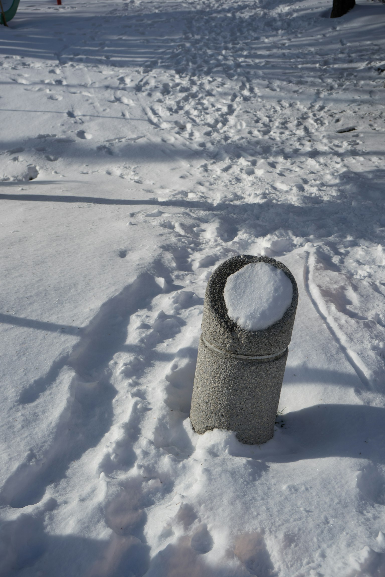 被雪覆盖的垃圾桶和雪中的脚印
