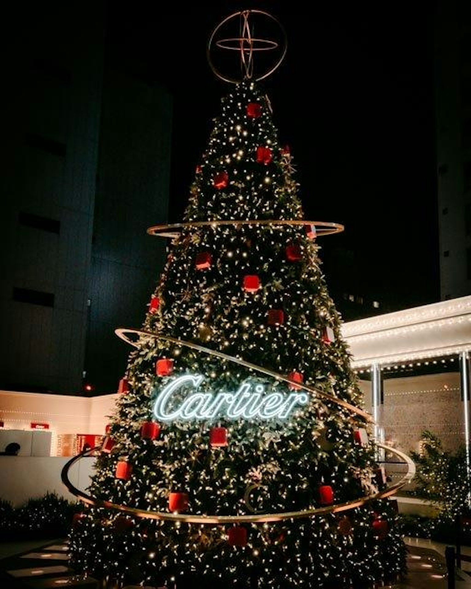 ต้นคริสต์มาสประดับด้วยโลโก้ Cartier และการตกแต่งสีแดงในบรรยากาศกลางคืน