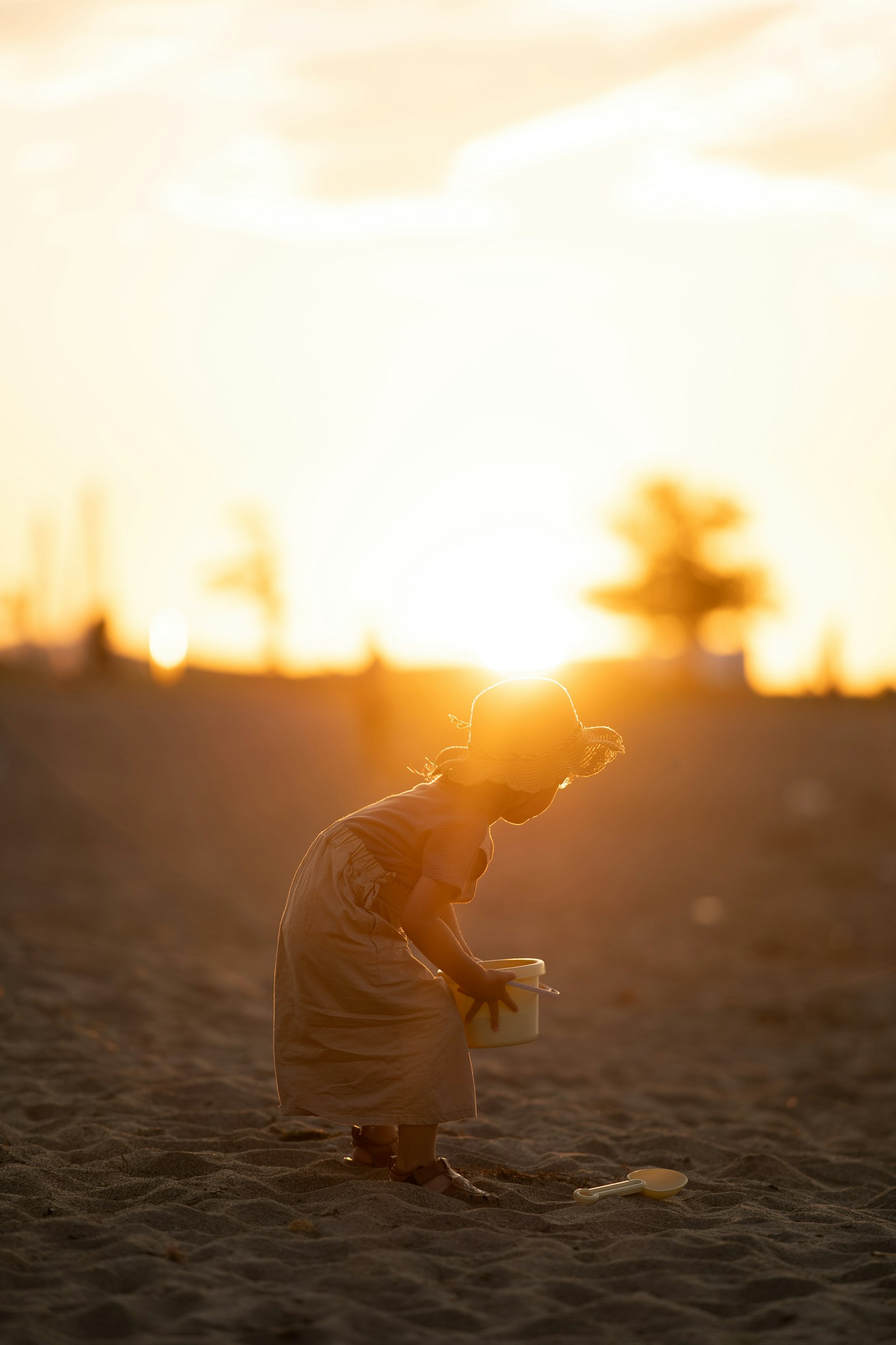 夕日を背にした砂浜で遊ぶ子供のシルエット