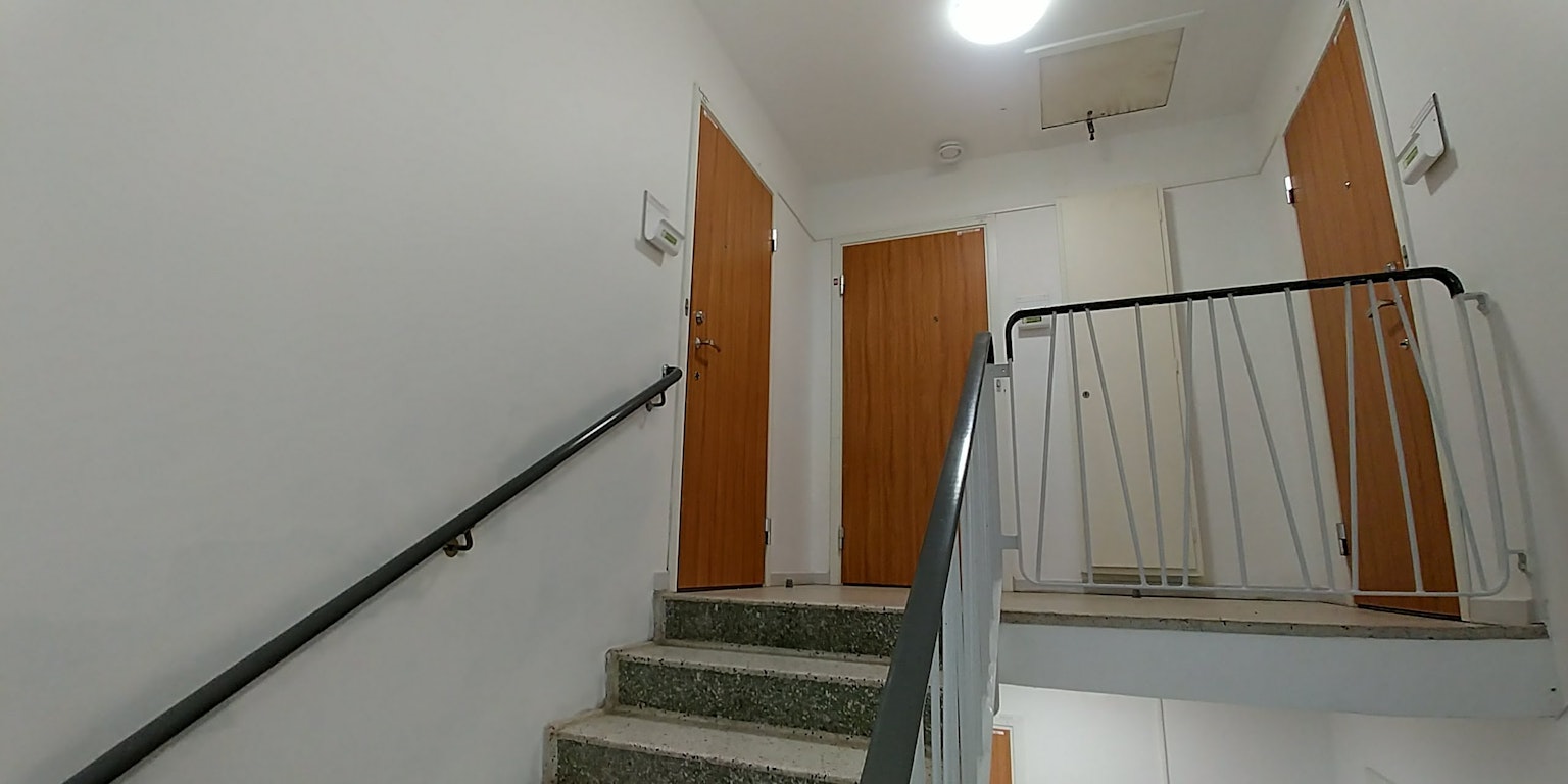 Couloir simple avec des murs blancs et des portes en bois en haut des escaliers