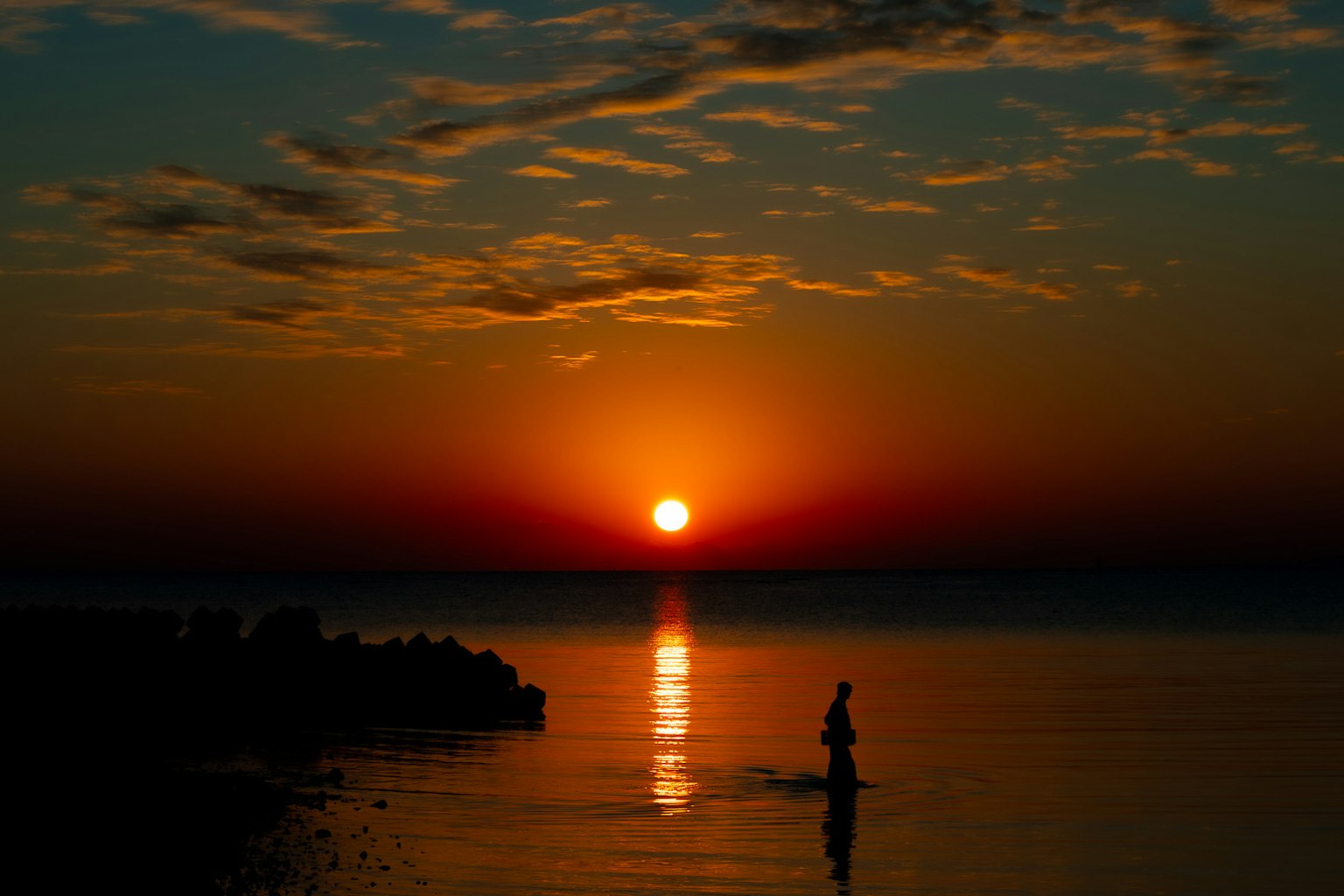 夕日が水面に反射する美しい風景とシルエットの人物