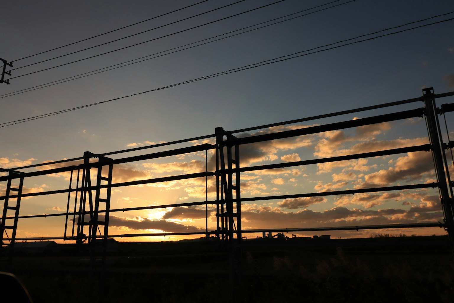 Silhouette d'une clôture en métal contre un coucher de soleil