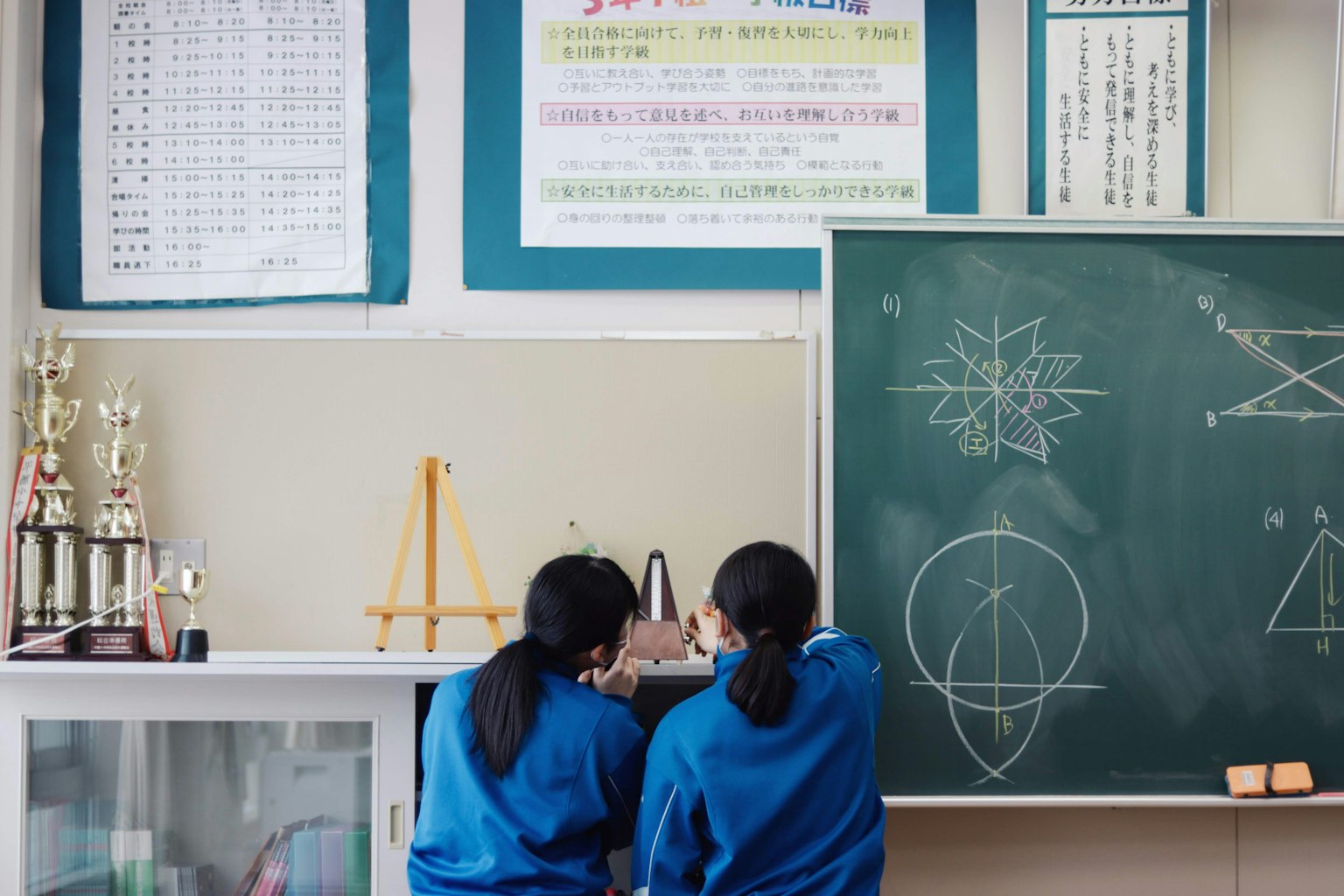 兩名學生站在教室的黑板前，查看數學公式