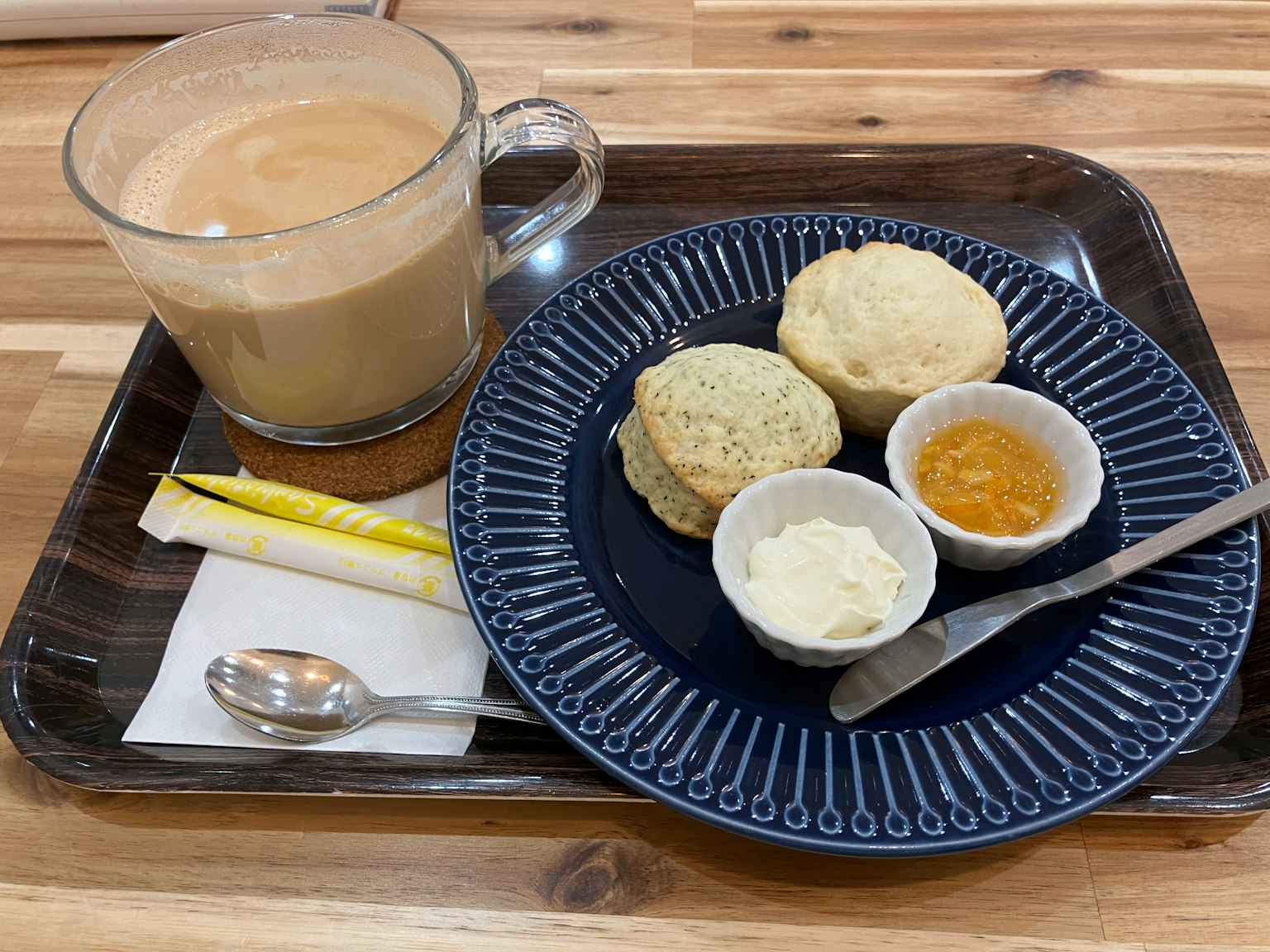 A tray with coffee, scones, butter, and honey served on a blue plate