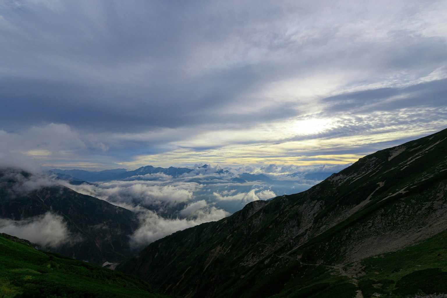 Vast landscape with mountains and clouds under a dramatic sky
