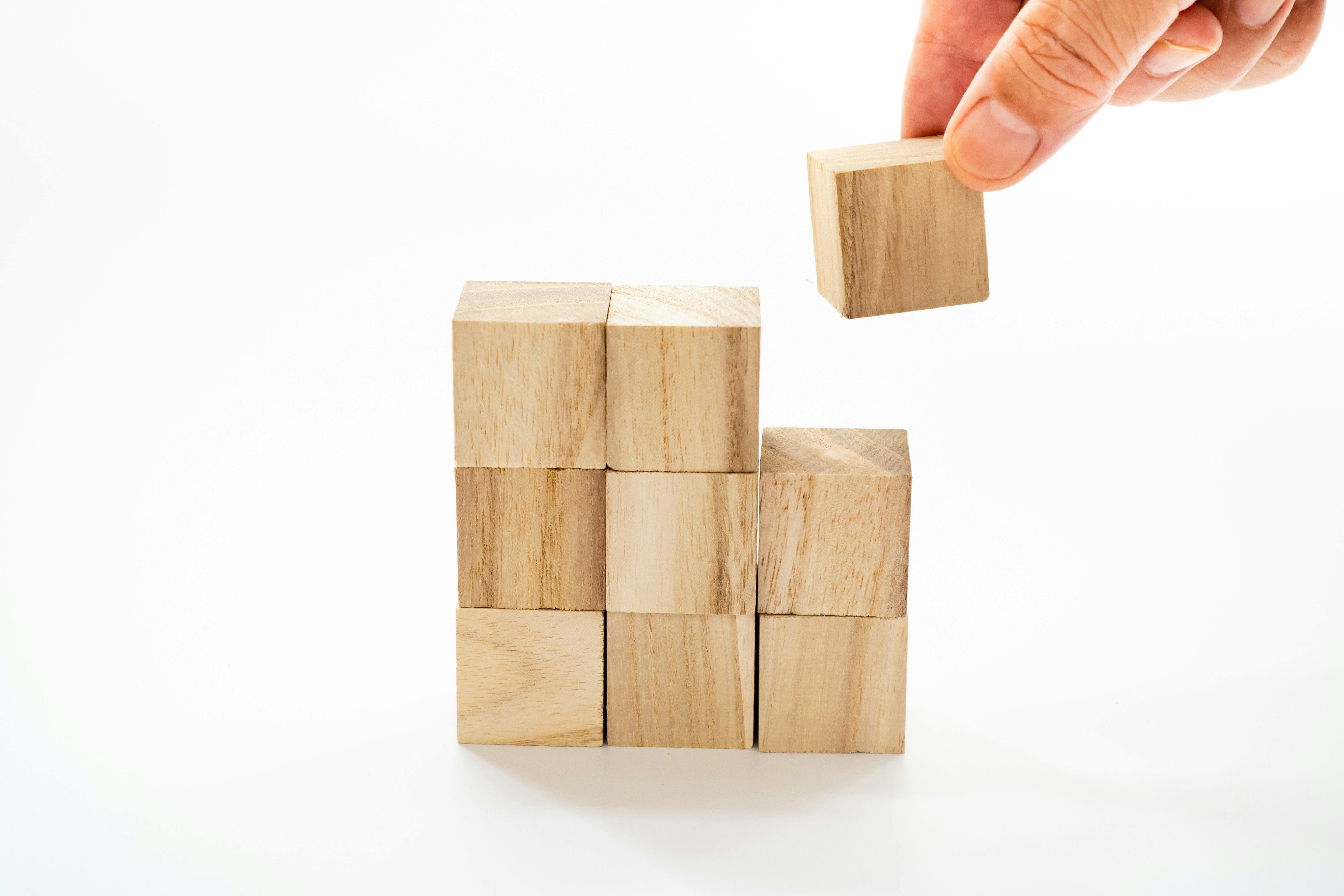 Hand moving wooden building blocks on a white background