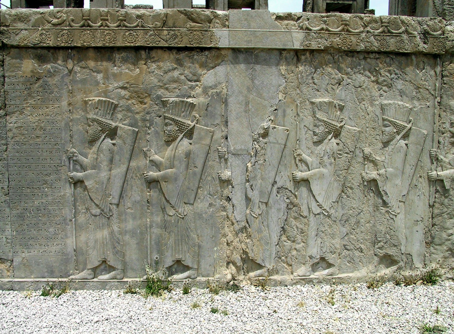 Ancient carved stone wall depicting a procession of figures
