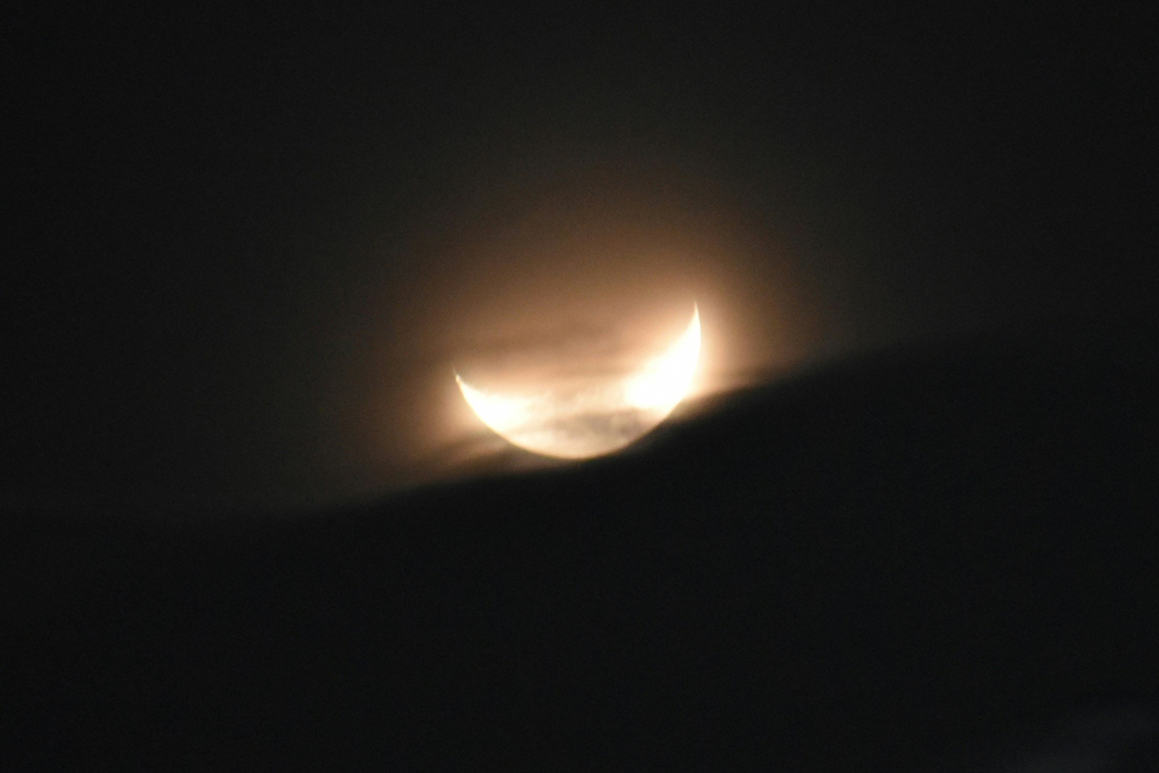 雲の間から見える三日月の夜空