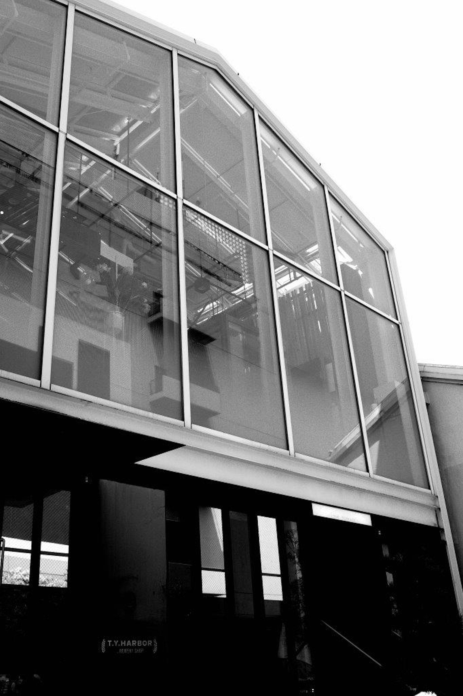 Monochrome image showcasing a modern glass building with a striking architectural design