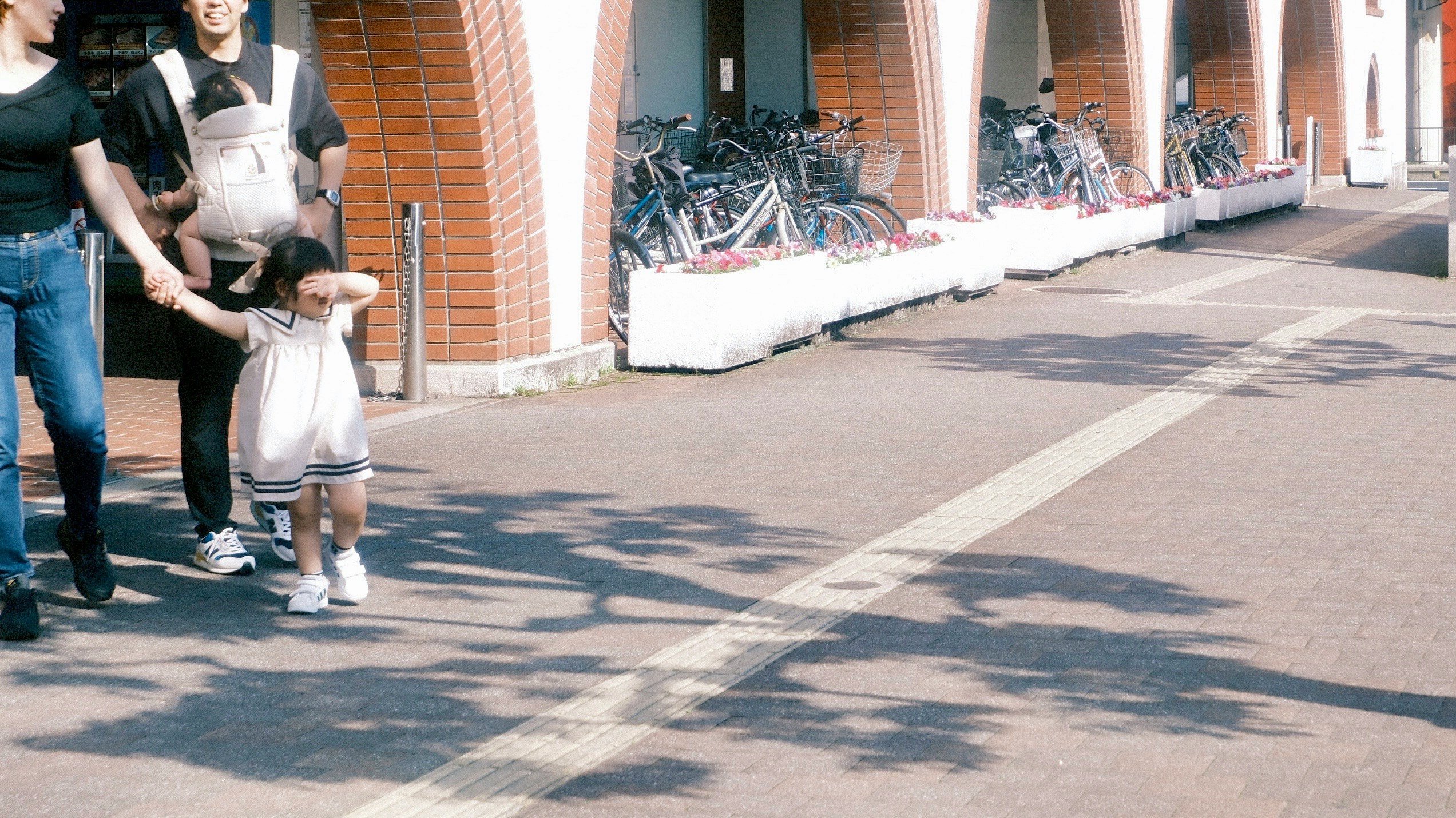 レンガ壁の路地でベビーカーを押す親子の散歩