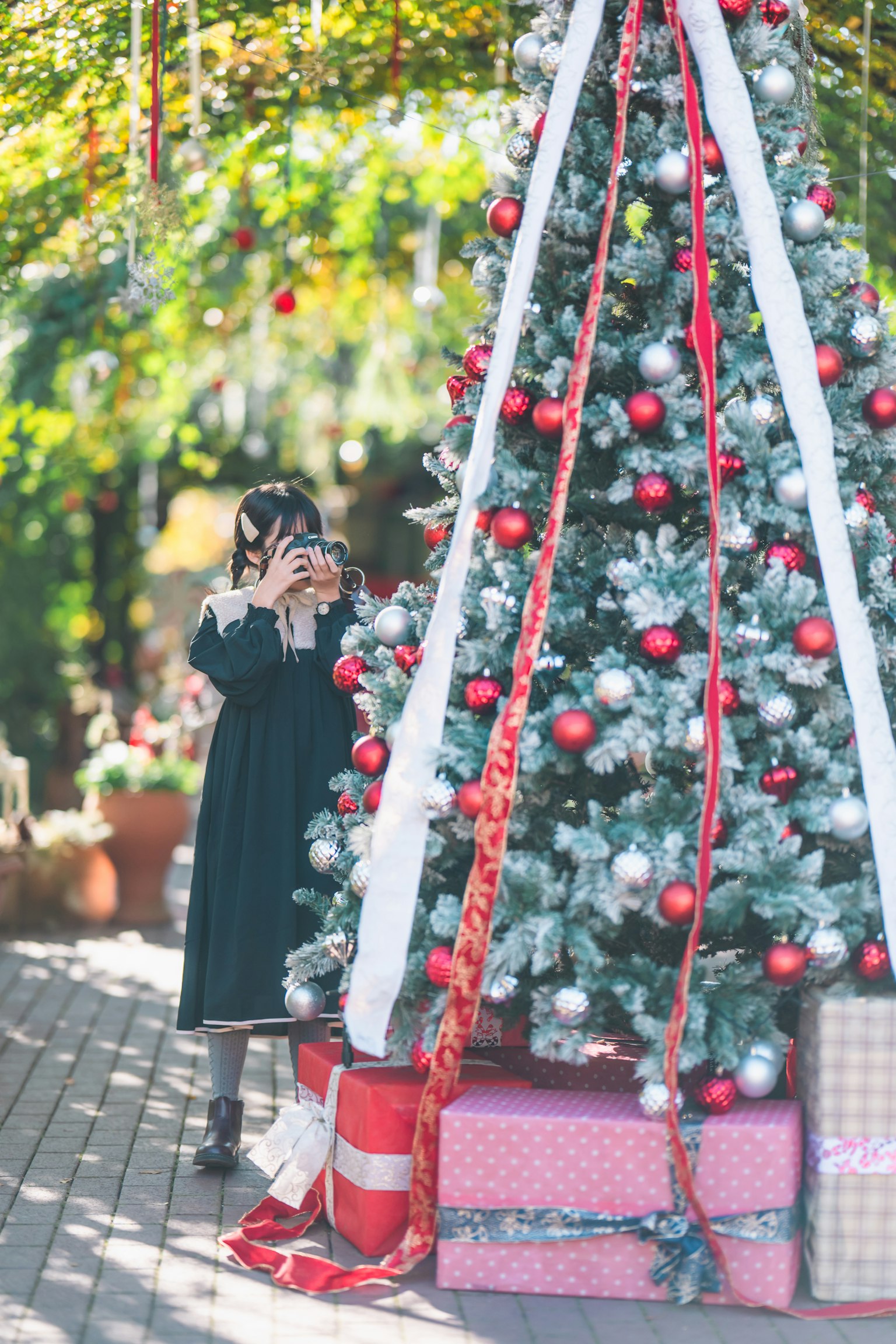 A child holding a camera in front of a Christmas tree