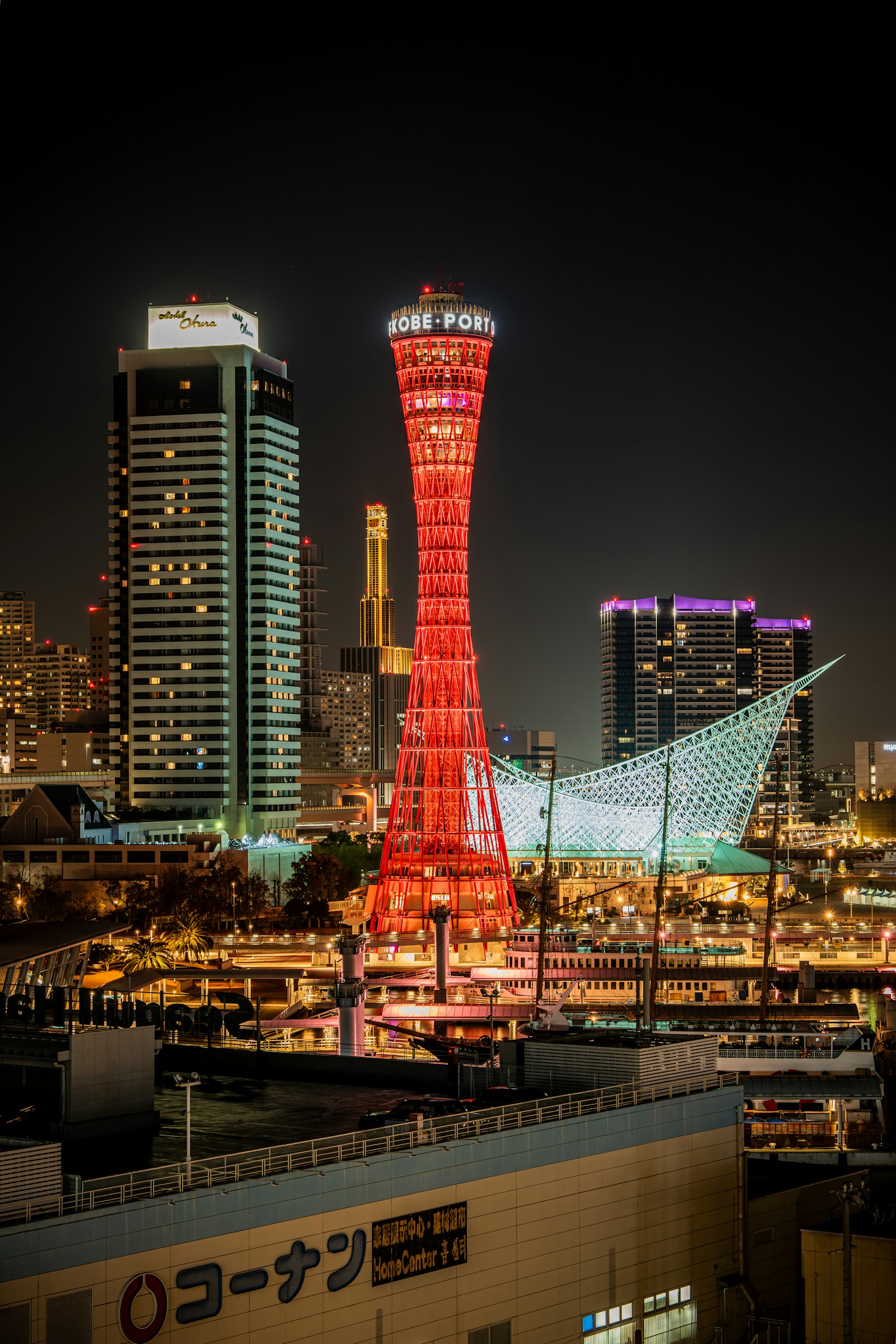 Tour portuaire rouge de Kobe illuminée la nuit avec des bâtiments modernes en arrière-plan