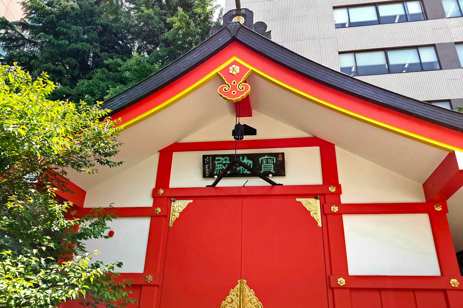神社入口有红色屋顶和华丽装饰 周围环绕着生机勃勃的绿色树木