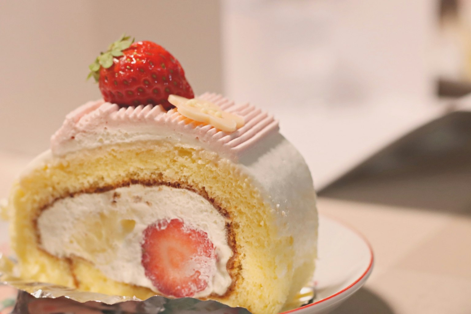Coupe transversale d'un gâteau roulé à la crème avec une fraise sur le dessus