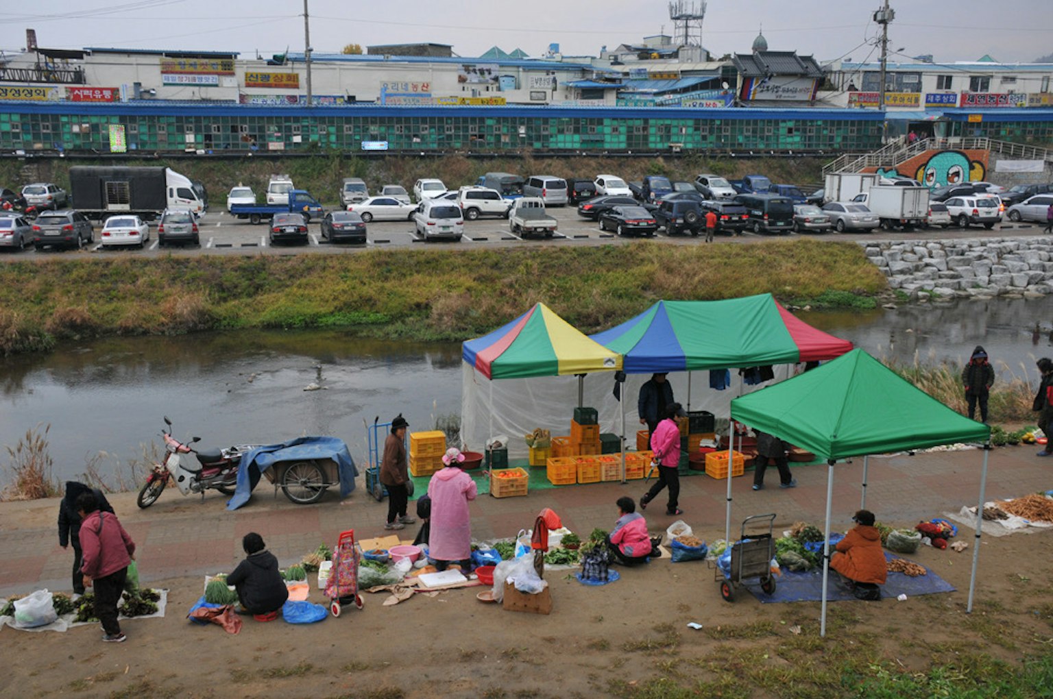 Cảnh chợ bên bờ sông với những chiếc lều màu sắc và con người