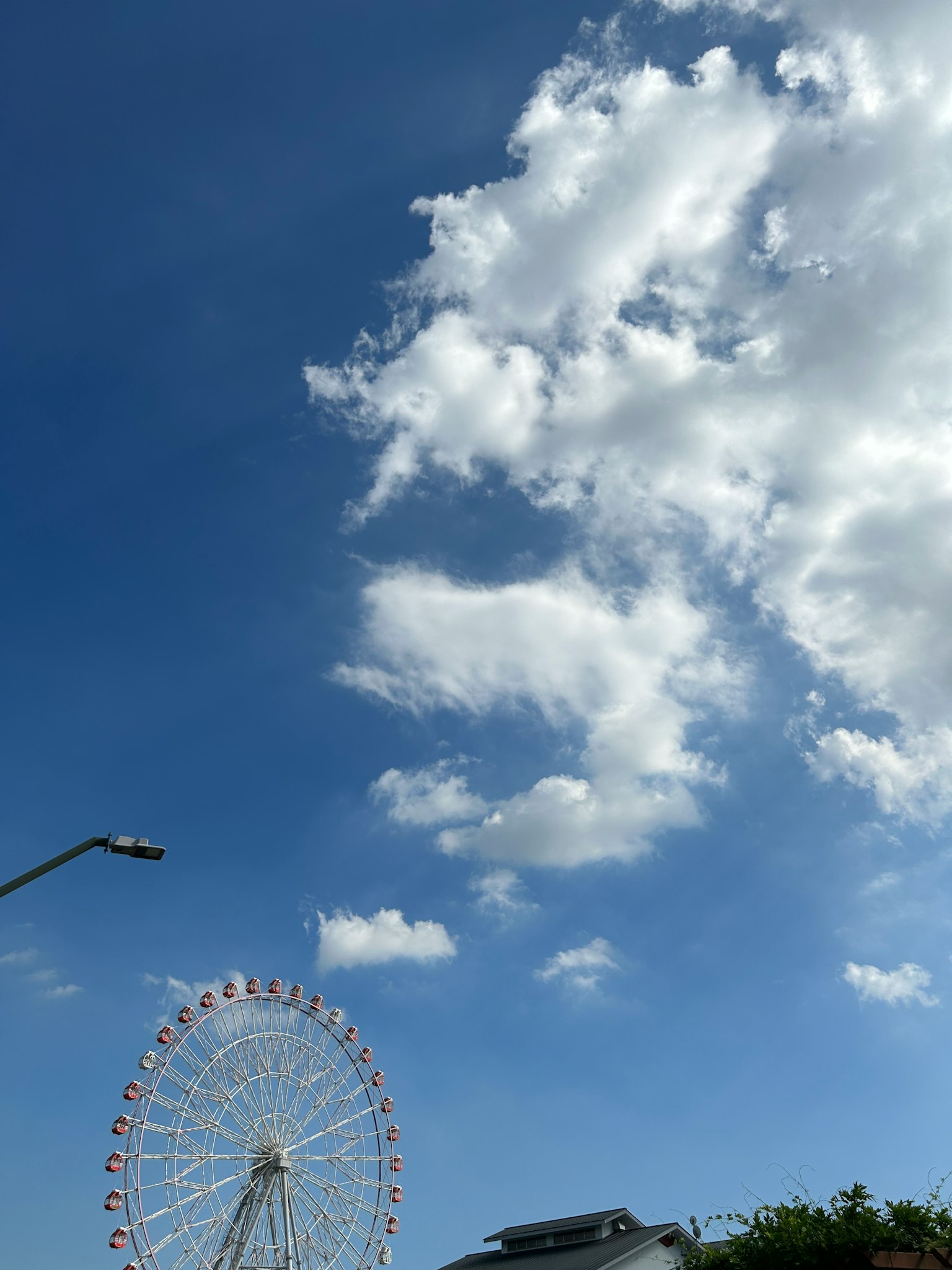 Vista di una ruota panoramica sotto un cielo blu con nuvole bianche