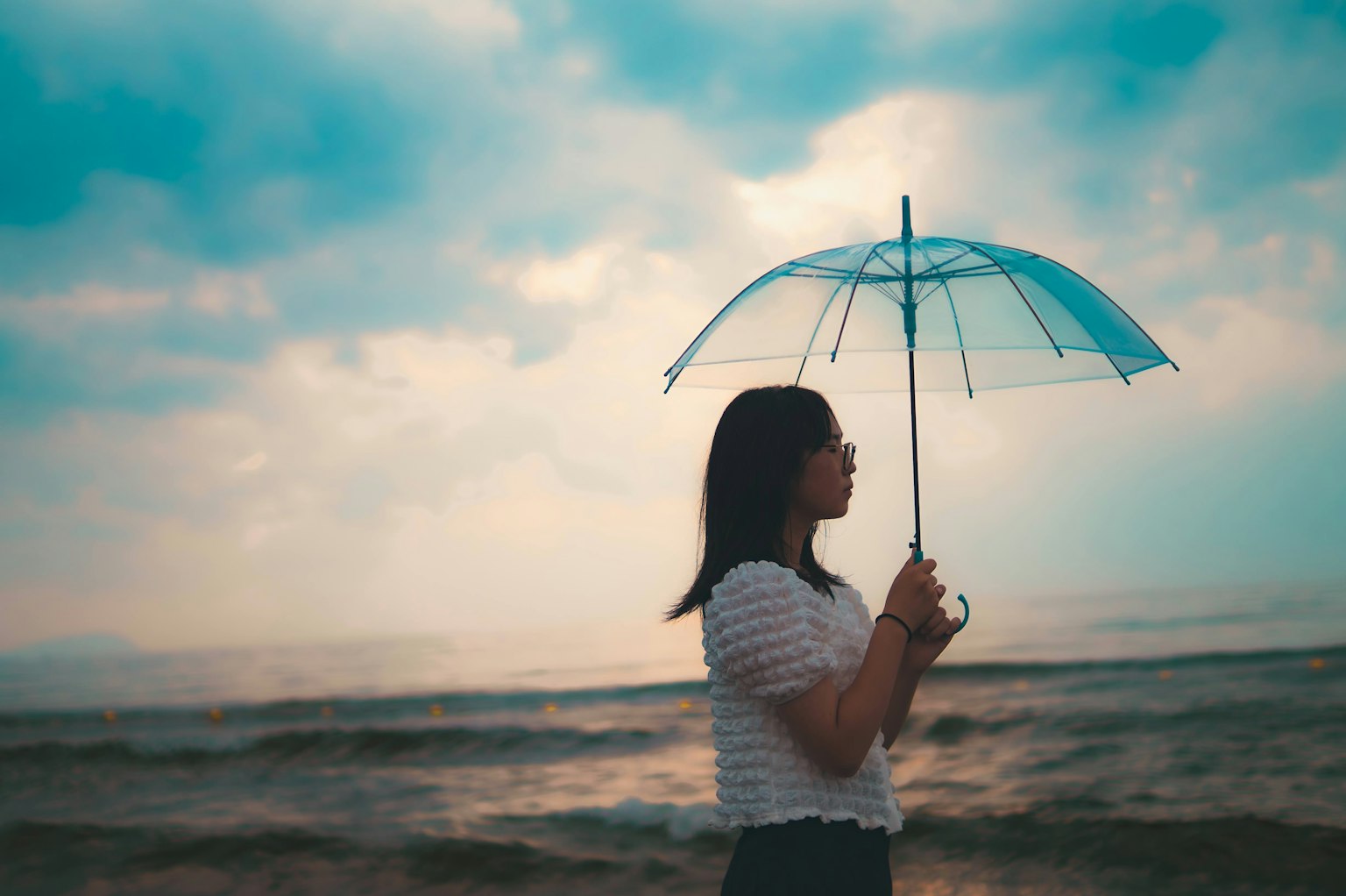 海邊撐傘的女性剪影與多雲的天空