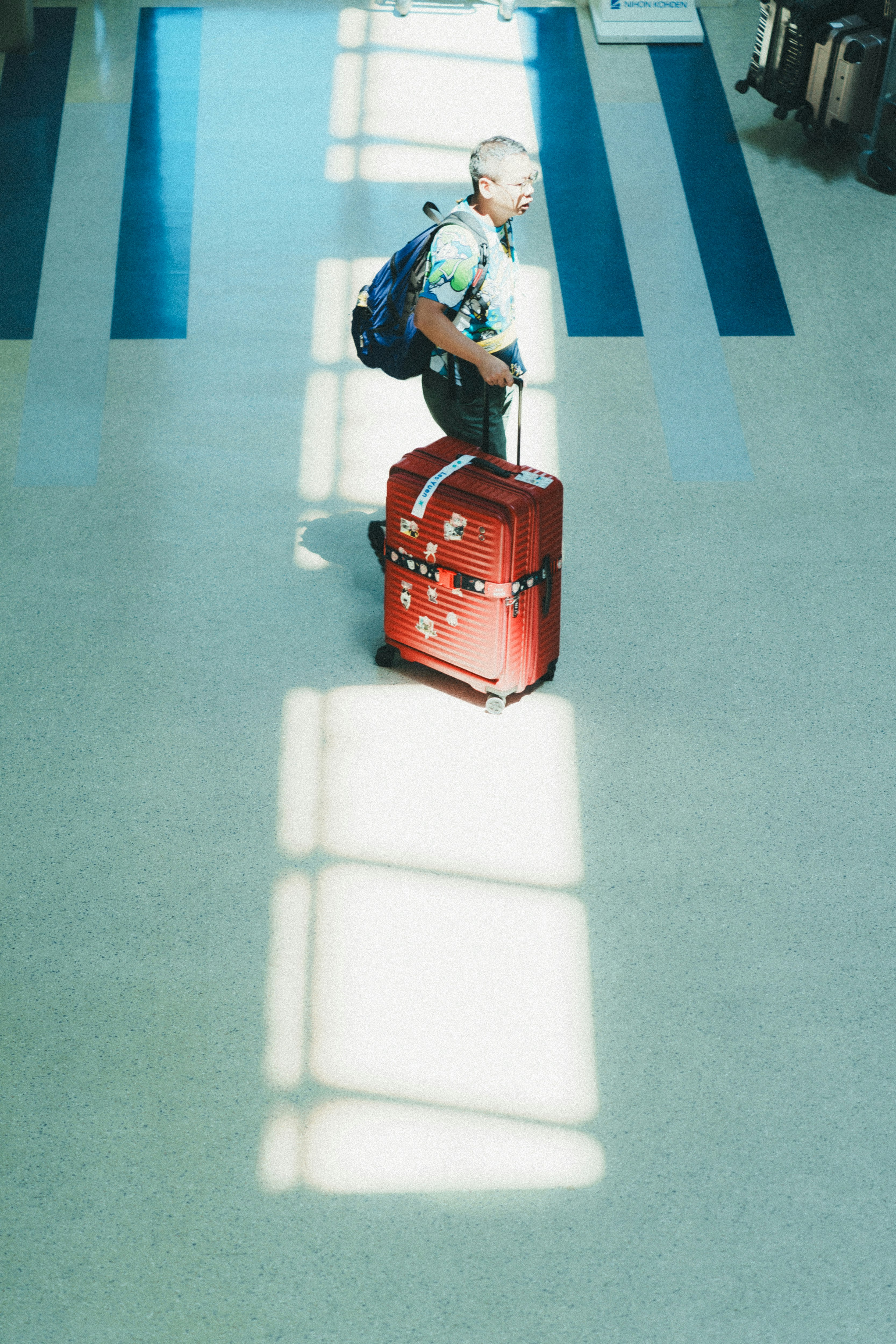 traveler with suitcase and backpack walking through a station corridor