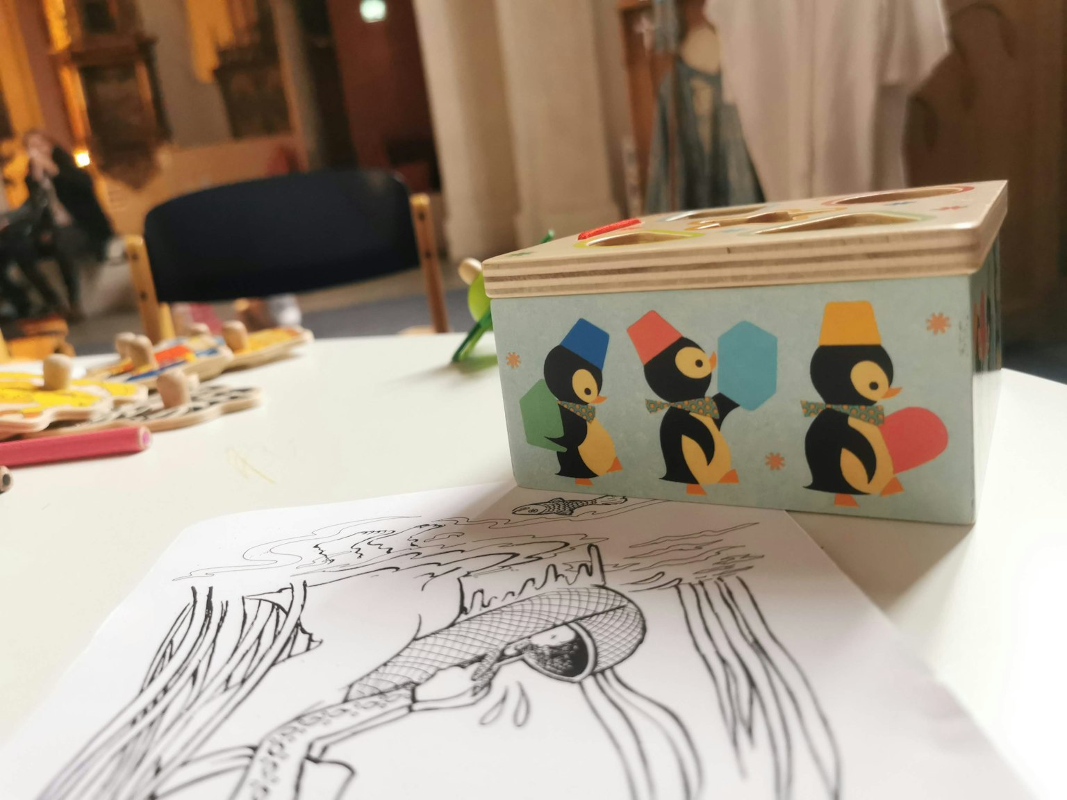 Boîte en bois colorée avec des illustrations de pingouins et une page à colorier sur la table