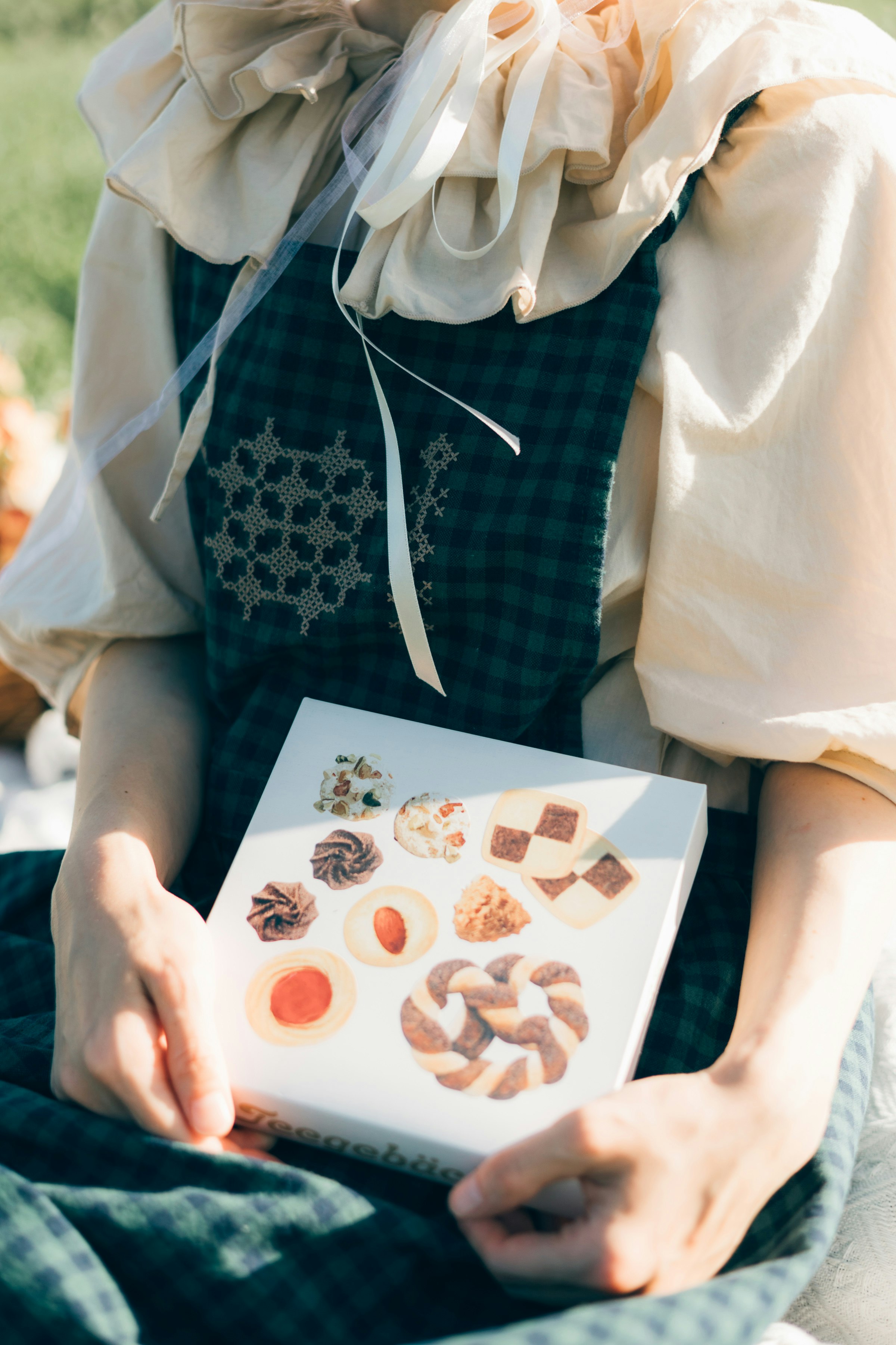リボン付き衣装の子どもが手作りのお菓子カードを見せる