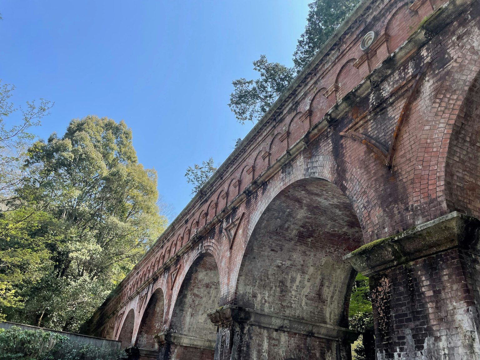 Antico ponte in mattoni con archi circondato da alberi verdi