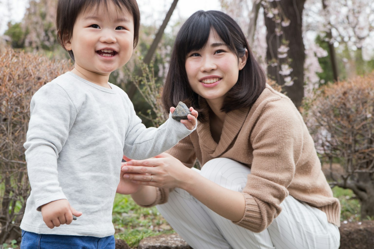 Lächelndes Kind und Mutter in einem Park mit Kirschblüten