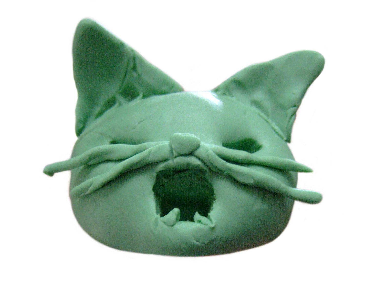 緑色の猫の顔の彫刻で、口を開けている特徴がある