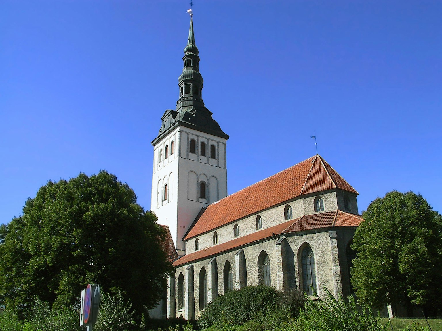 Historisches Kirchengebäude unter blauem Himmel mit rotem Dach und hohem Turm