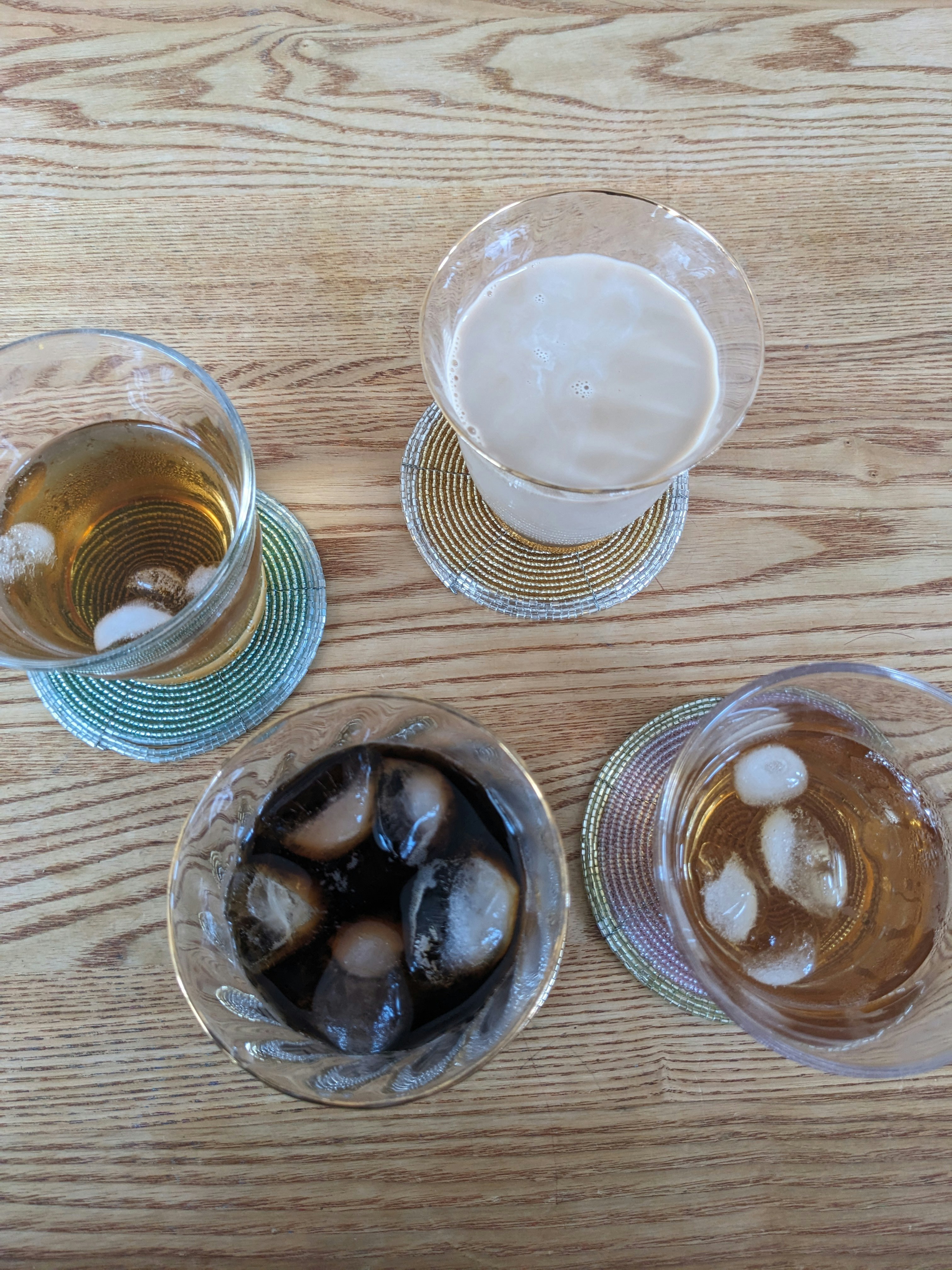 木目のテーブルに並ぶ4種類の飲み物のグラス