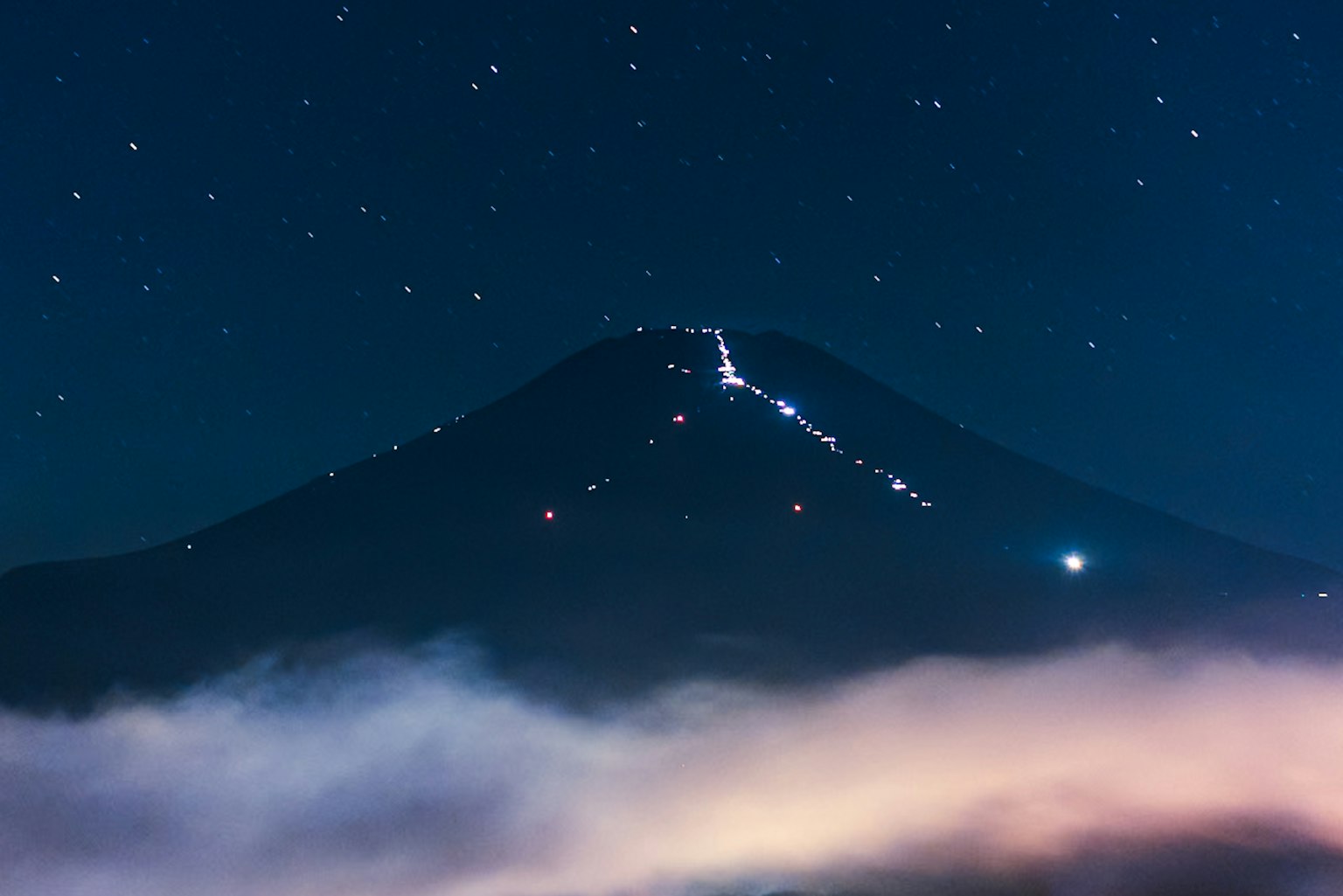Paisaje montañoso bajo un cielo estrellado Estrellas brillantes y un mar de nubes
