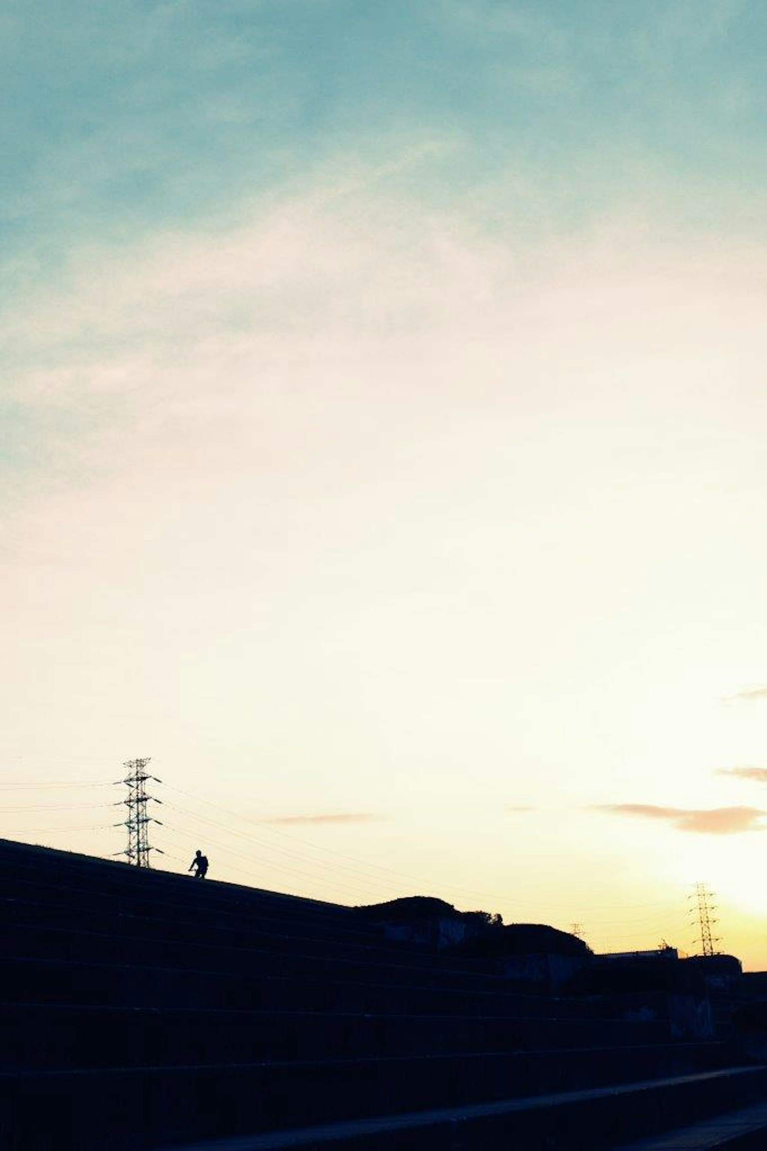 蓝天和夕阳下山丘的轮廓与电线