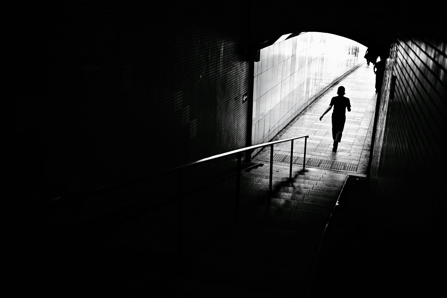 Silueta de una persona de pie en la salida de un túnel oscuro