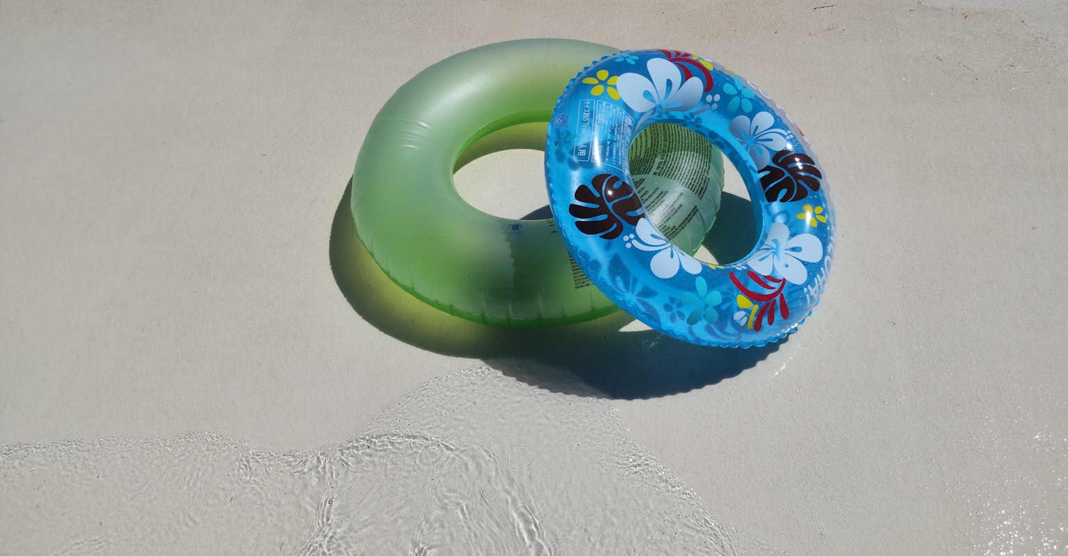 Green and blue floral patterned inner tubes overlapping on a light surface