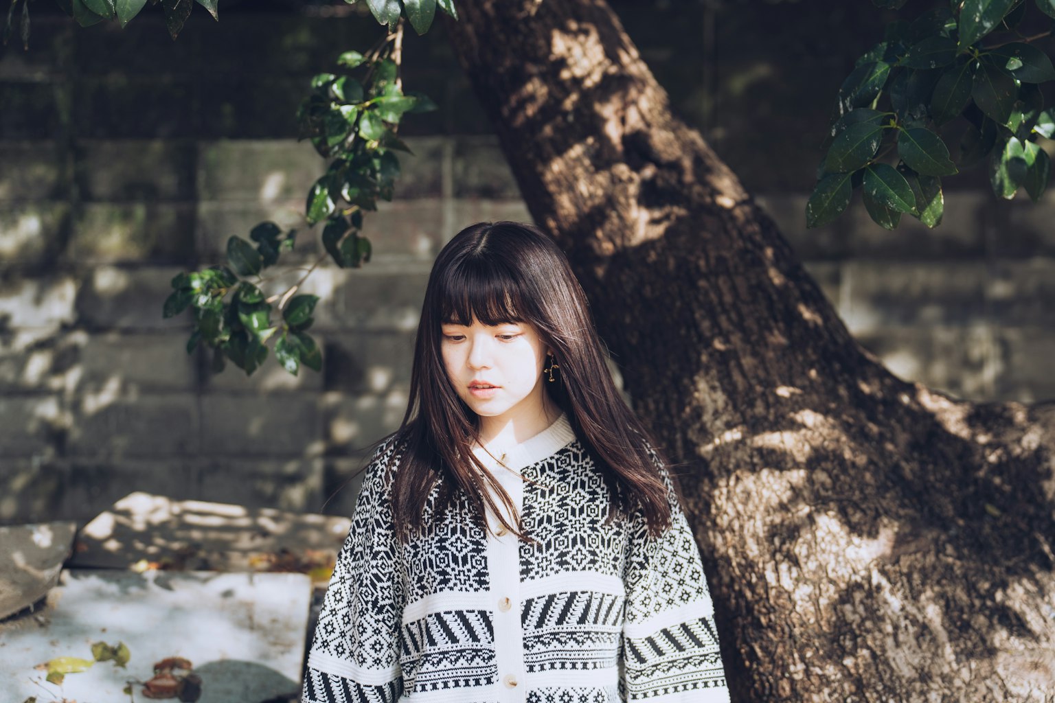 Une femme se tenant sous un arbre portant un pull monochrome