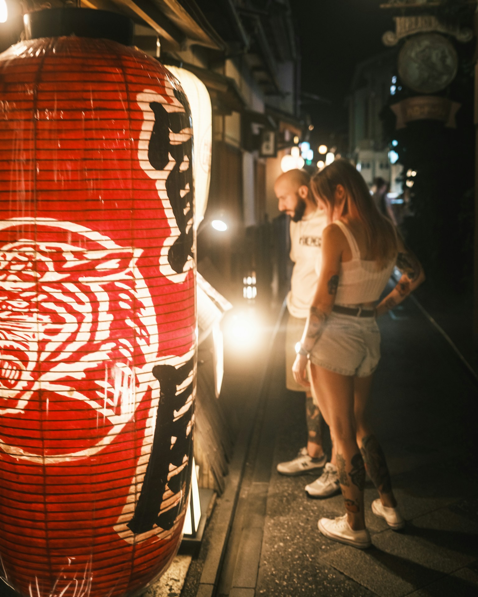 Couple admirant une grande lanterne rouge dans une rue nocturne