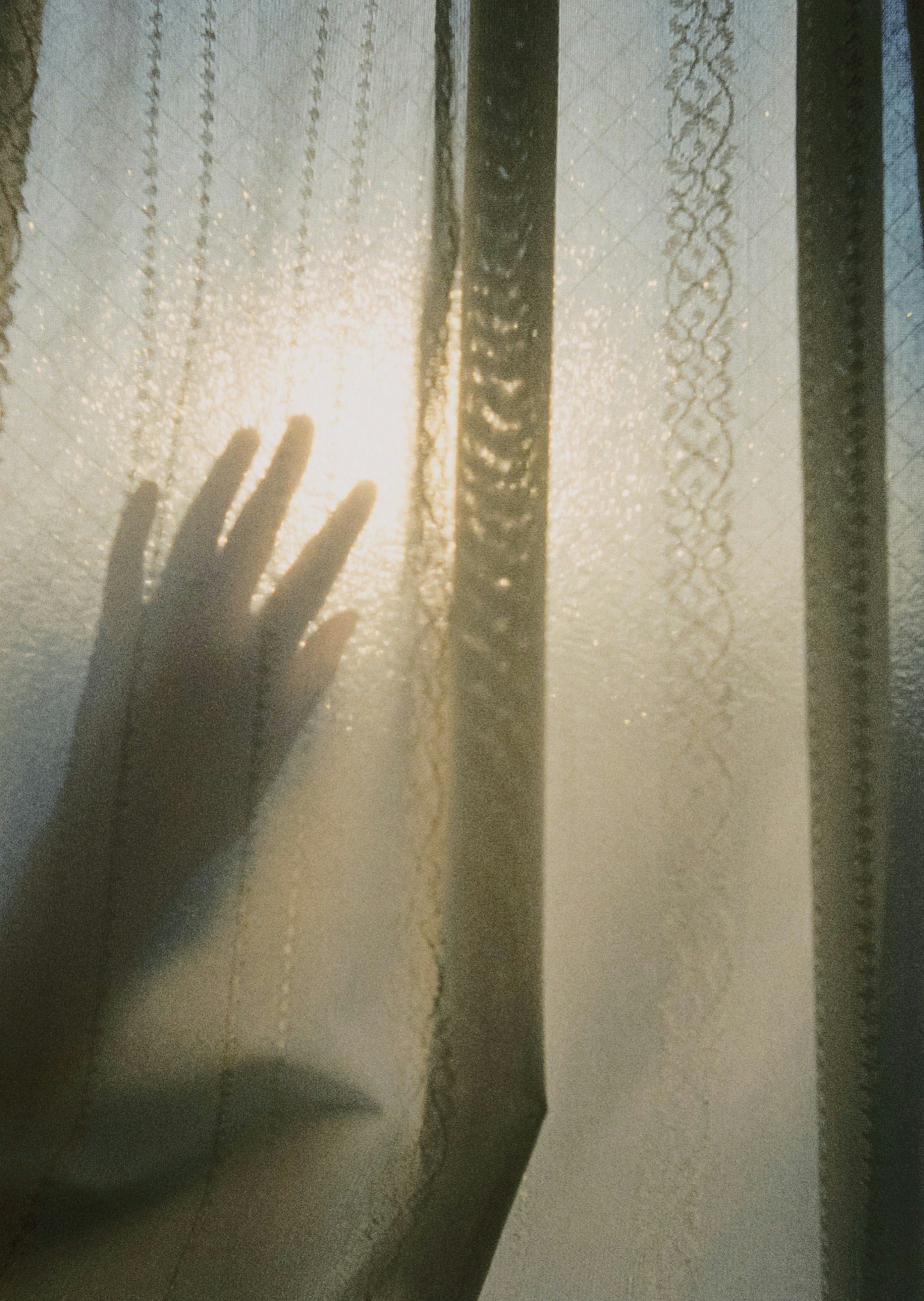 Silhouette einer Hand hinter einem transparenten Vorhang mit sanftem Licht