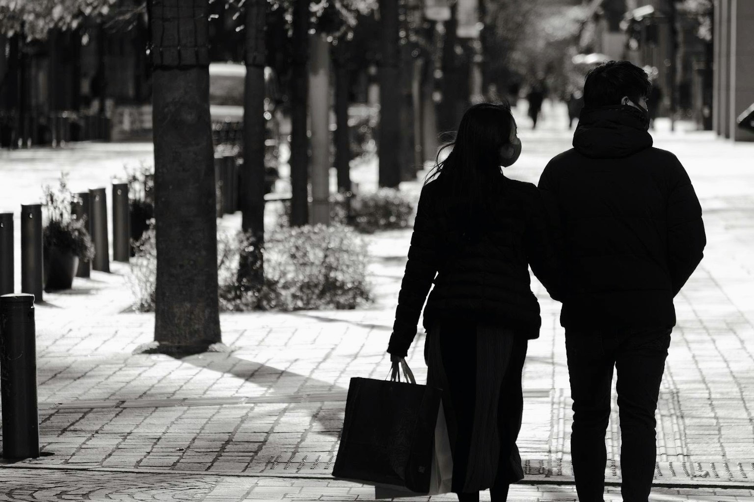 Cặp đôi nắm tay nhau đi trên phố thành phố trong bộ áo khoác đen