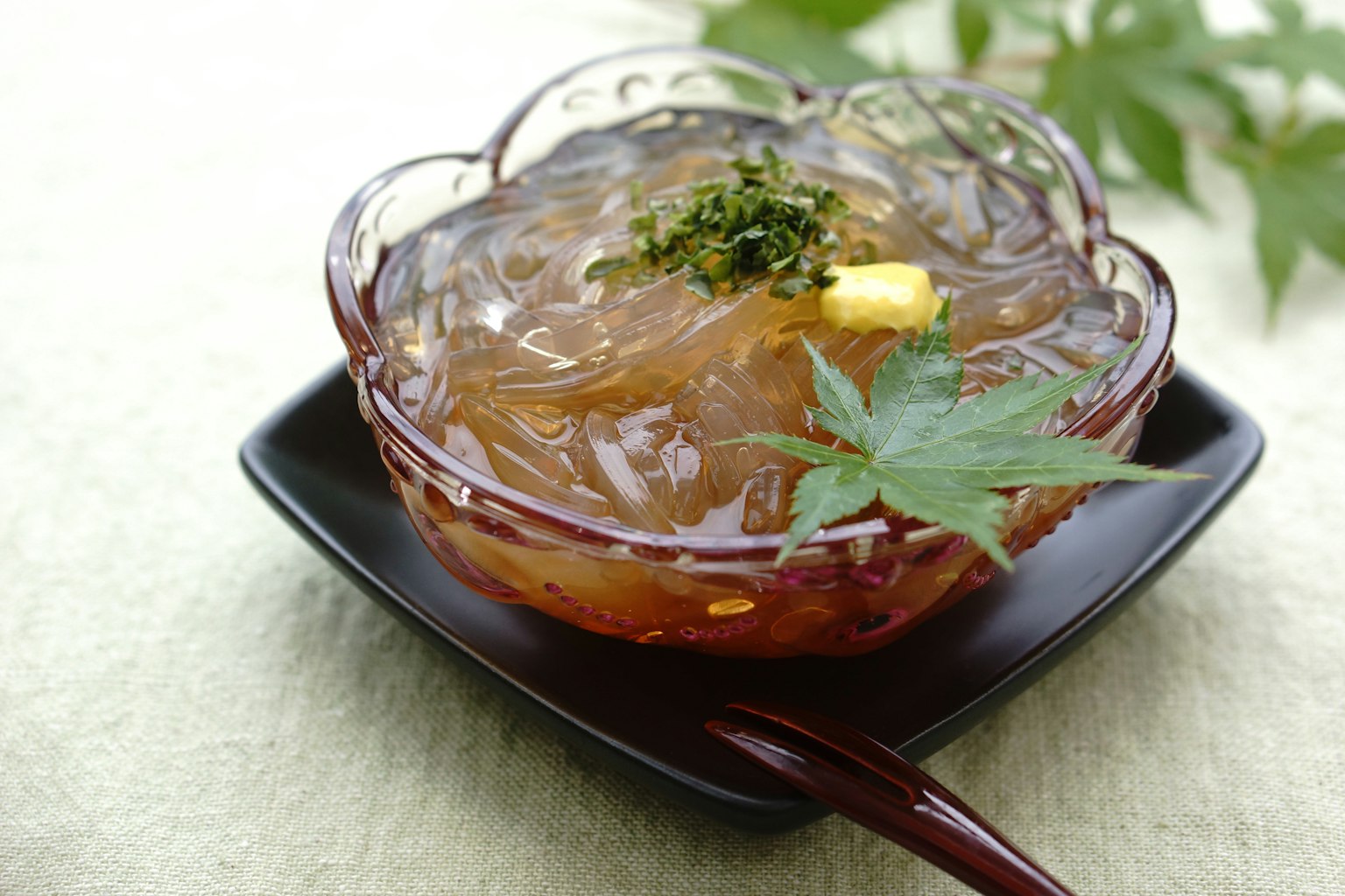 一个装满透明琼脂果冻的美丽甜点碗，上面装饰着绿色叶子和一片柠檬