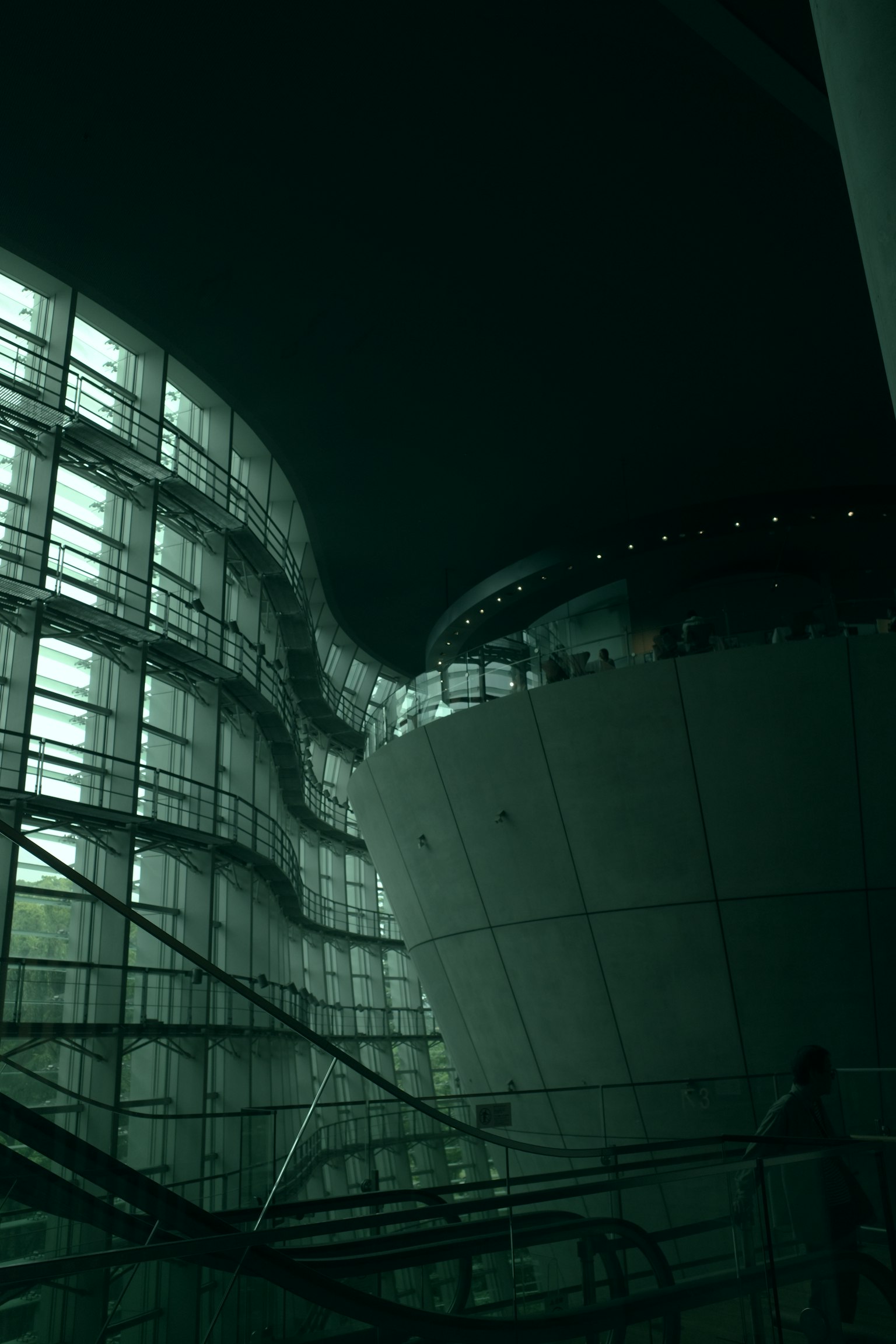 Vista nocturna de una estructura arquitectónica moderna con líneas curvas y fachada de vidrio