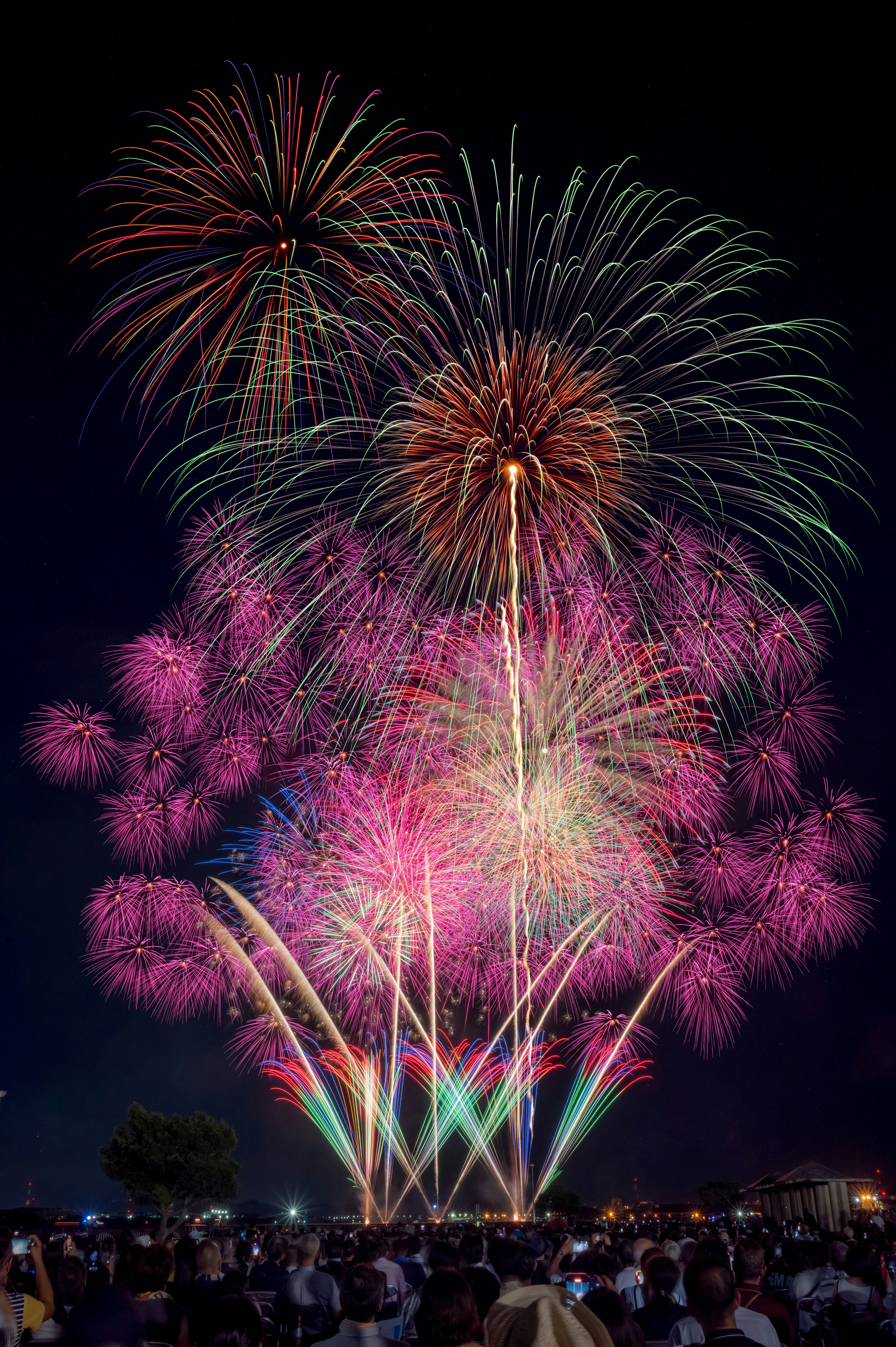 夜空に咲く色とりどりの花火と観客のにぎわい