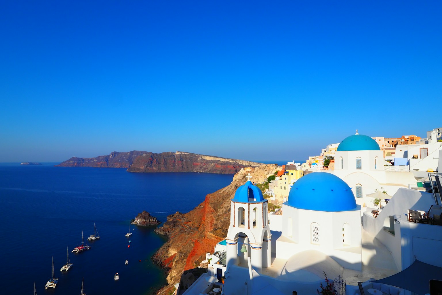 ทิวทัศน์ชายฝั่งของซานโตรินีที่มีโบสถ์โดมสีน้ำเงินและอาคารสีขาว