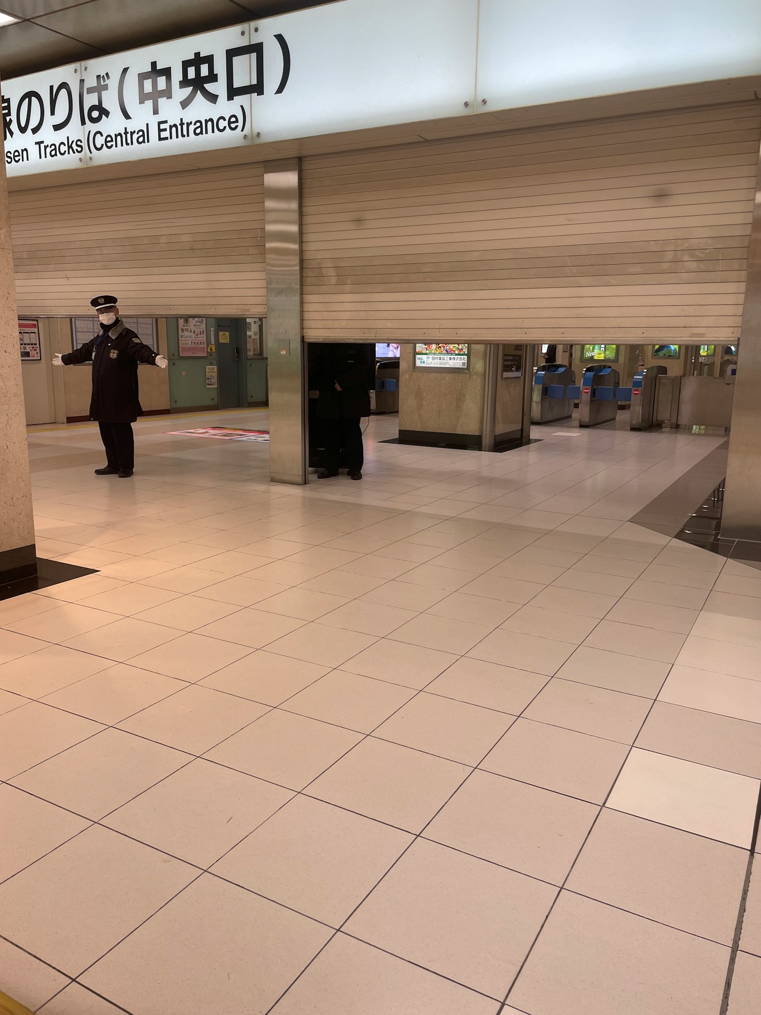 Interior of a train station with shuttered central entrance and security guard